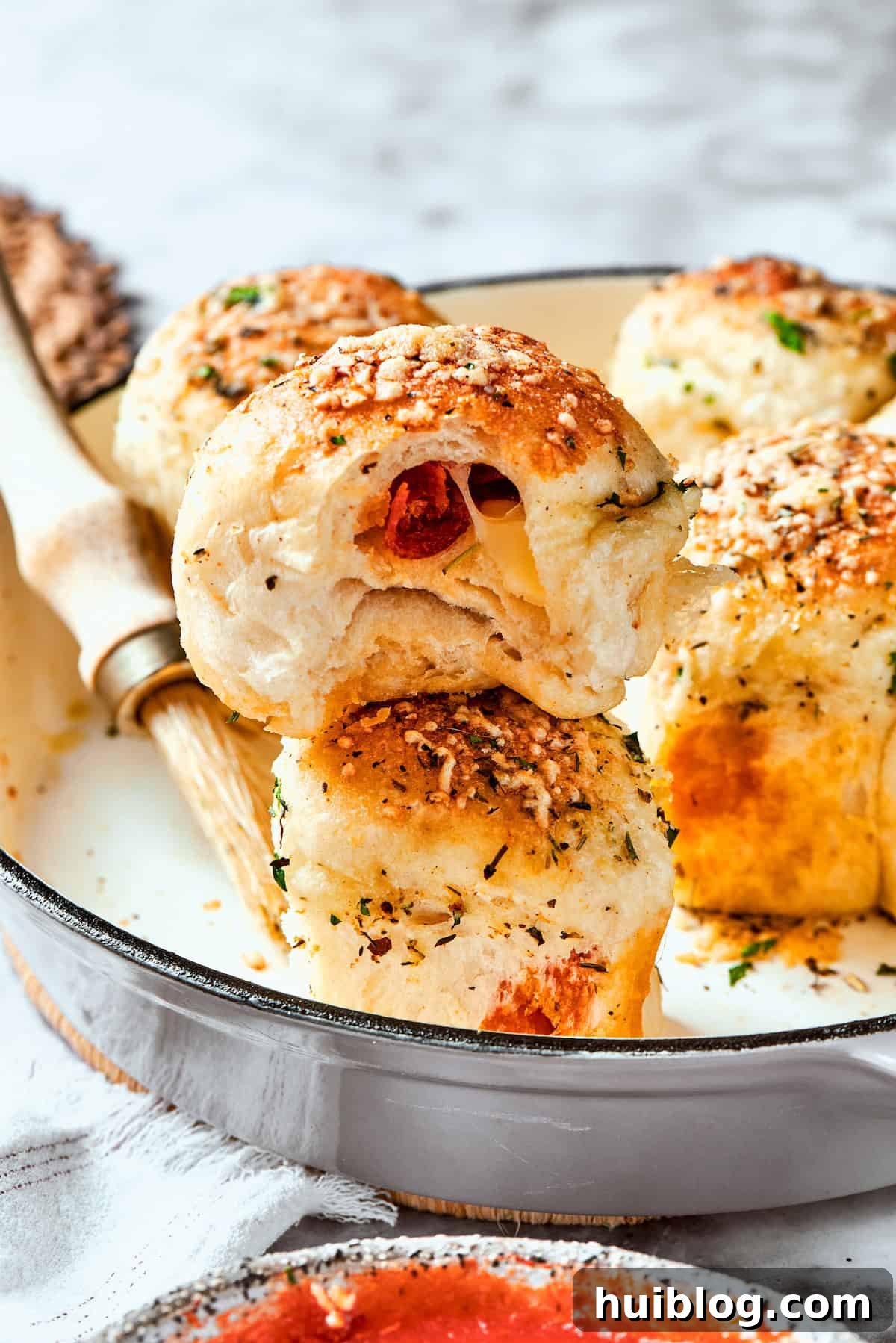 Serving up a hot and fresh pizza bite. A serving utensil lifts out a perfectly baked pizza bite from a skillet, showing its golden crust.