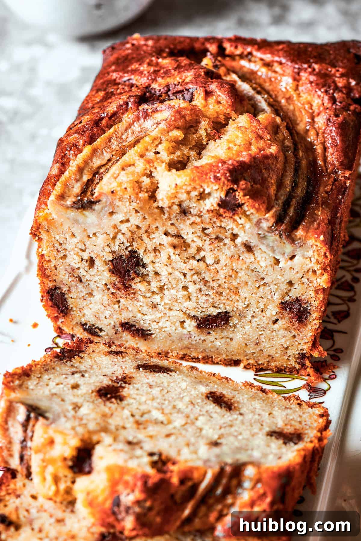 A close-up view of a perfectly sliced Sour Cream Banana Bread, revealing its tender, moist interior studded with melted chocolate chips, ready to be enjoyed.
