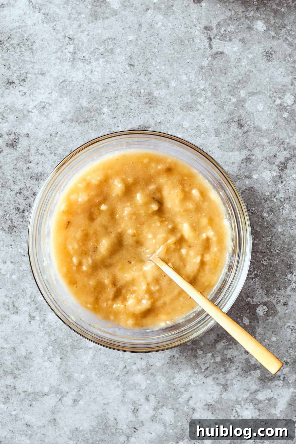 The smooth, mashed bananas are gently folded into the luscious wet mixture, blending their sweet flavor with the other liquid ingredients.