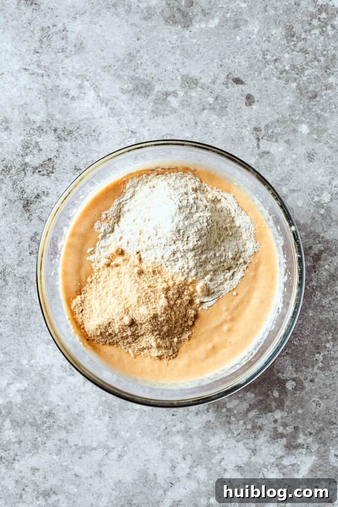 A delicate blend of all-purpose flour and almond flour is carefully added to the vibrant wet mixture, ready to be combined into a smooth batter.
