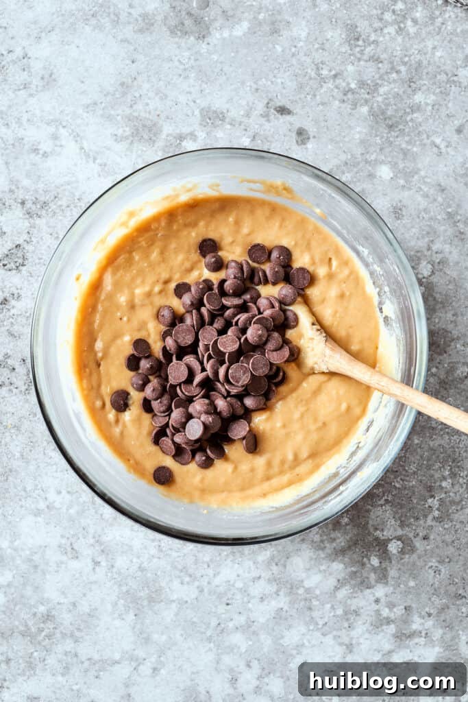 Generous chocolate chips are folded into the smooth banana bread batter, ensuring sweet pockets of flavor in every slice.