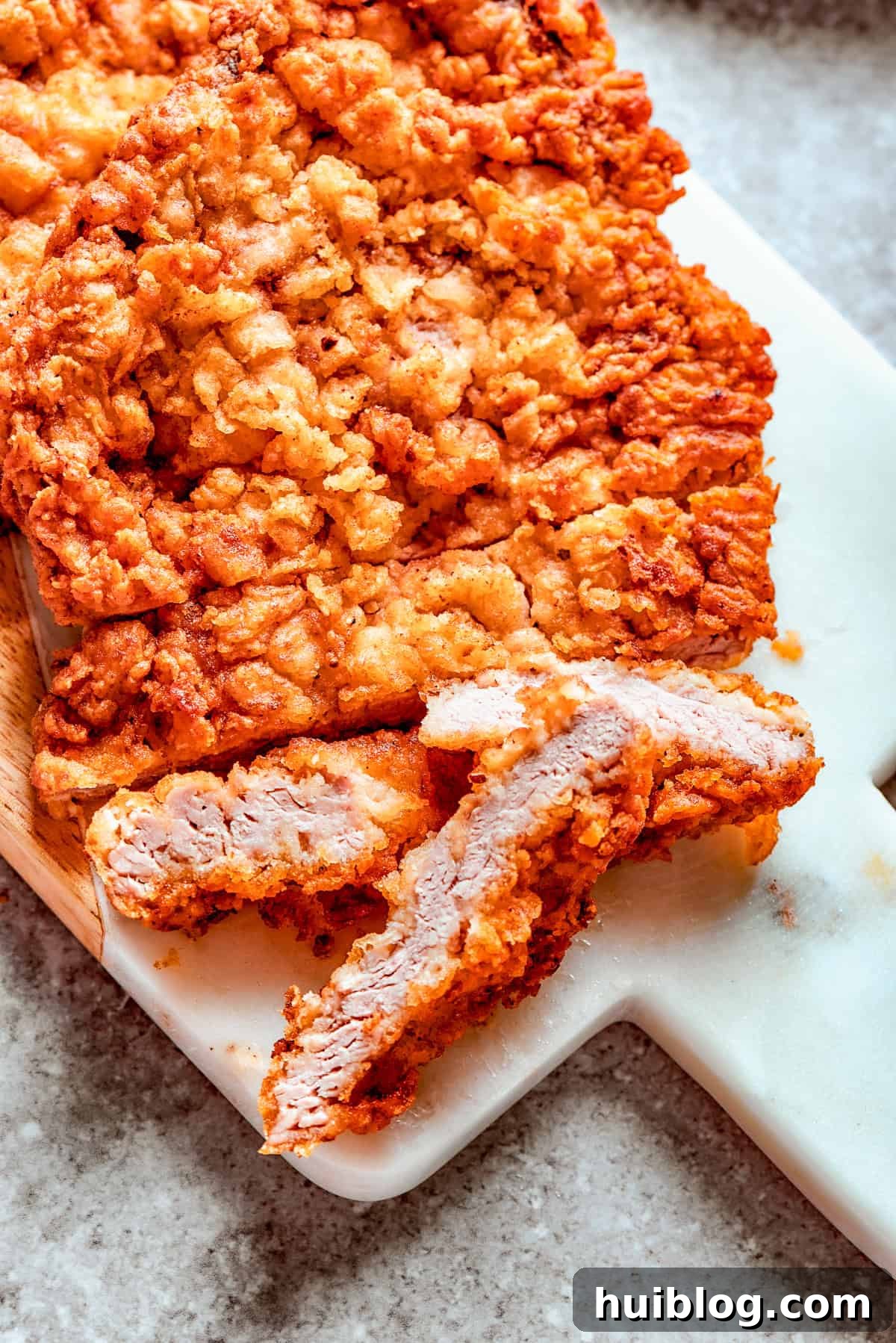 Breaded chicken fried steak on a cutting board.