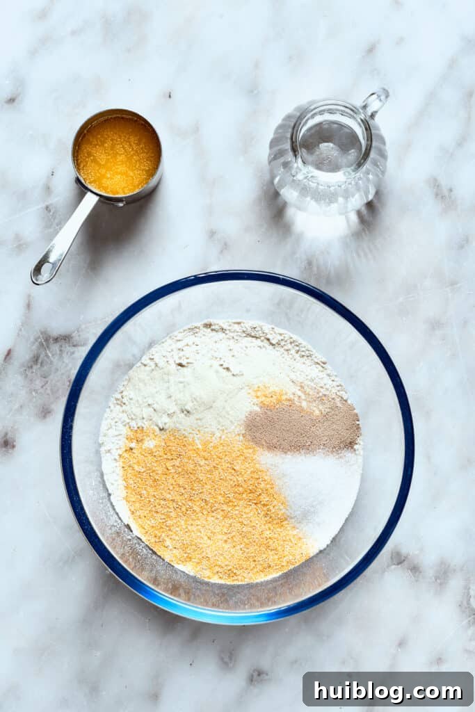 The dry ingredients for deep dish pizza crust, including flour, cornmeal, yeast, sugar, and salt, are shown in a large mixing bowl.
