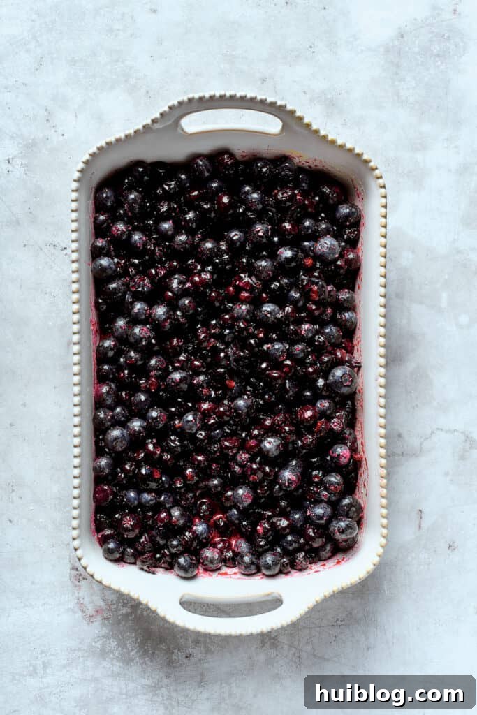 Bursting with juicy berries, this Blueberry Crisp Recipe is topped with a buttery brown sugar and oat crumble. The filling for blueberry crisp is spread out in a pan.