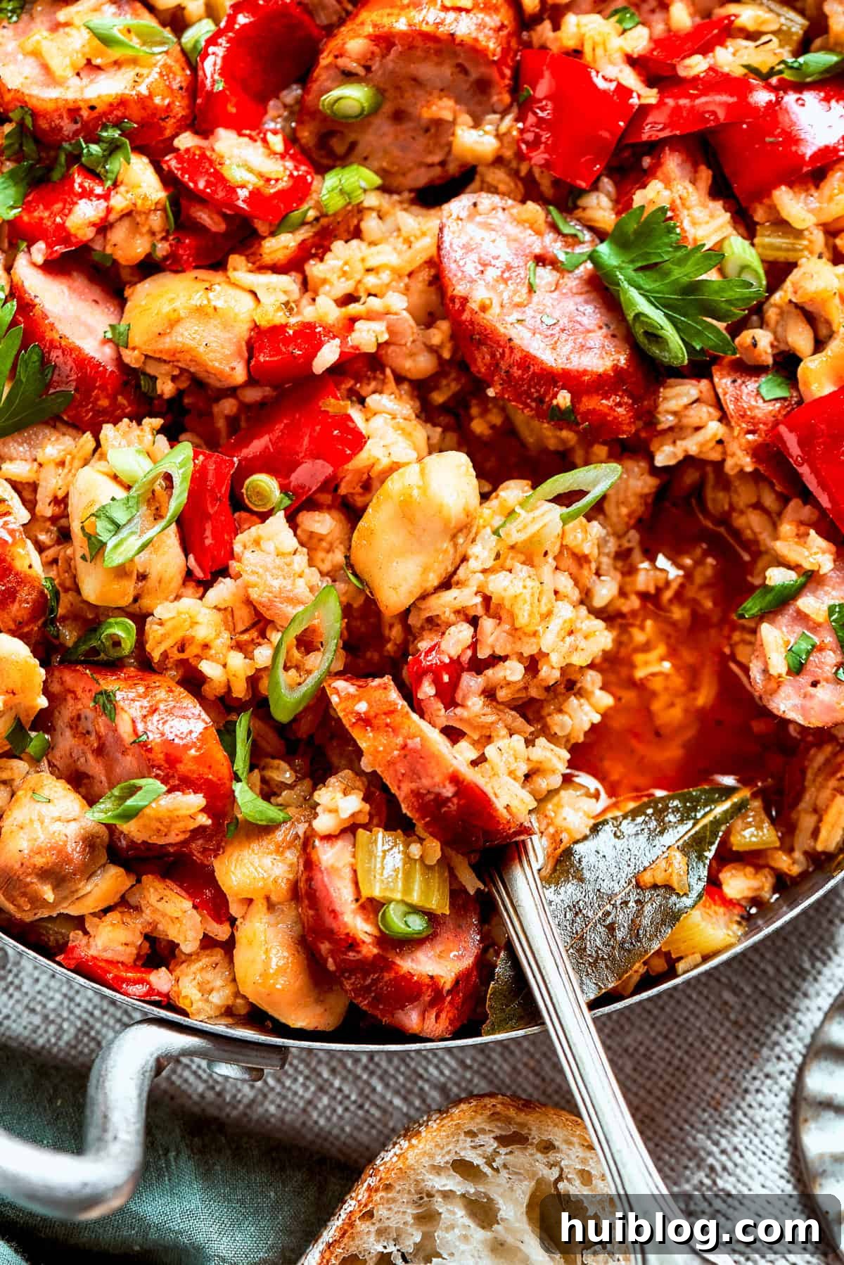 A large pot of perfectly cooked Chicken and Sausage Jambalaya, being stirred with a serving spoon, highlighting the rich texture of the rice, chicken, and sausage, ready to be dished out.