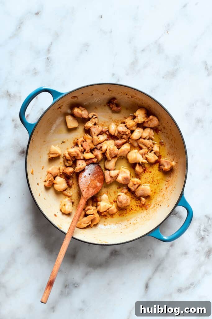 Close-up of chicken pieces browning beautifully in a skillet, creating a flavorful fond at the bottom of the pan.