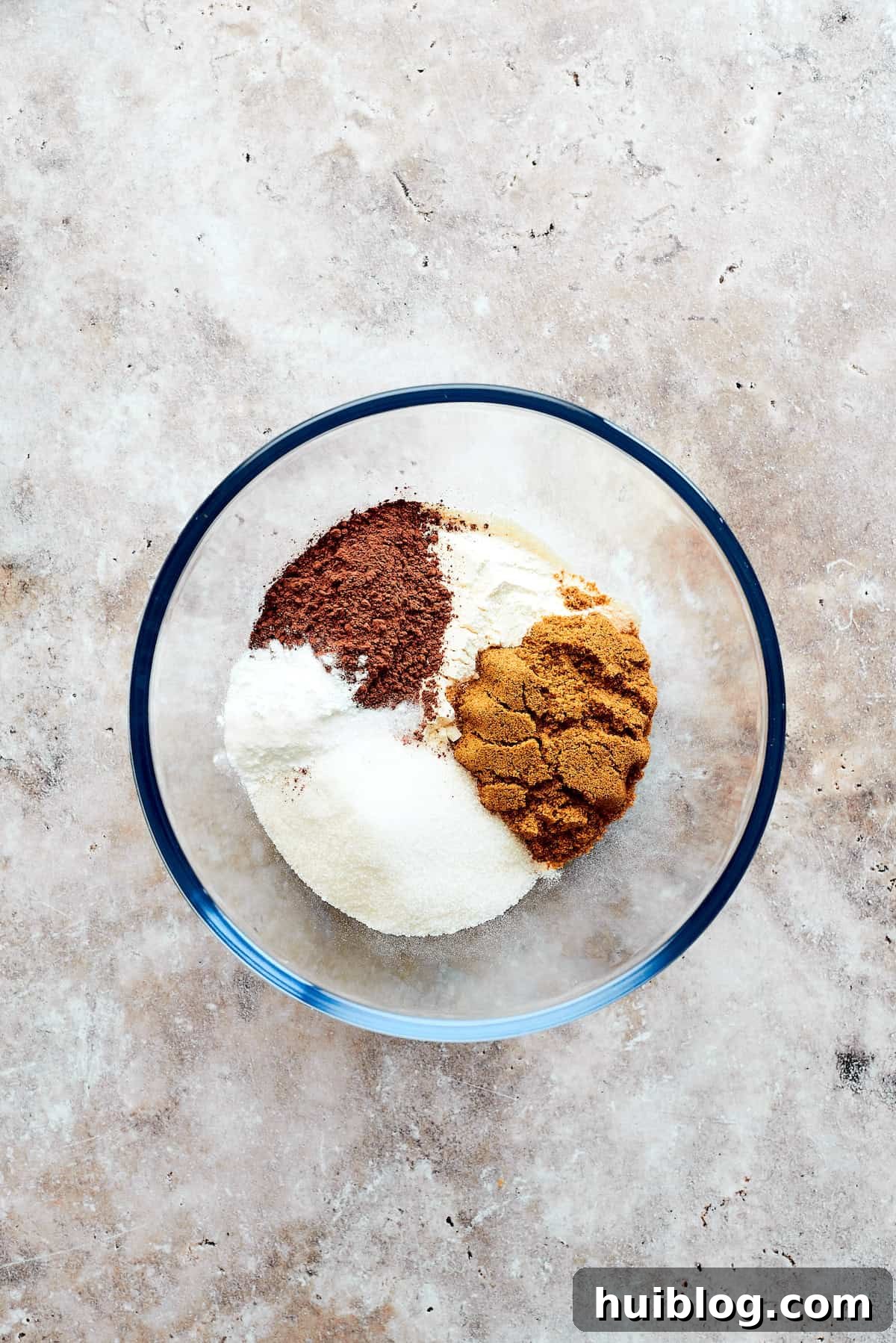 Flour, cocoa powder, and sugars are added to a bowl.