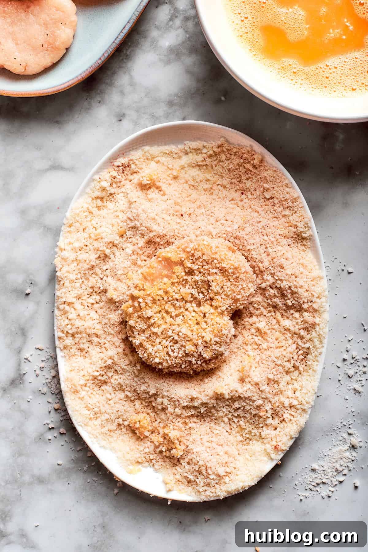 A breaded chicken nugget is shown, perfectly coated and ready for frying or baking.