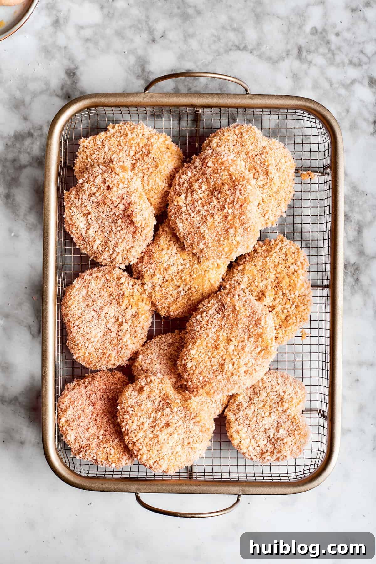 A basket full of breaded, uncooked chicken nuggets, ready to be fried.