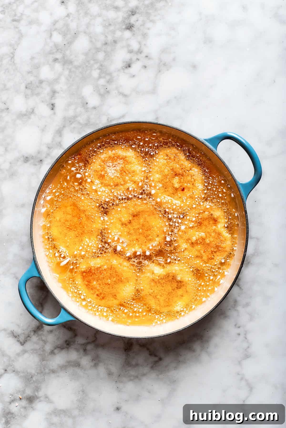 Golden-brown chicken nuggets sizzling in hot oil in a pan, achieving their crispy texture.