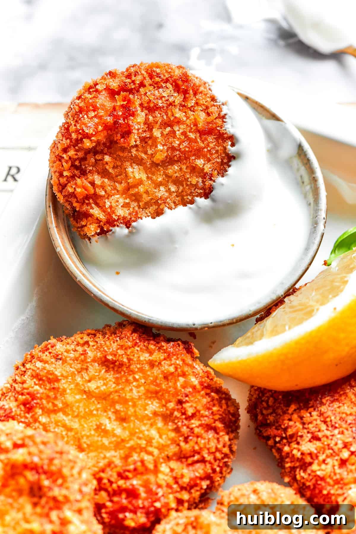 A golden-brown homemade chicken nugget being dipped into a creamy ranch sauce, highlighting its perfect crisp exterior.