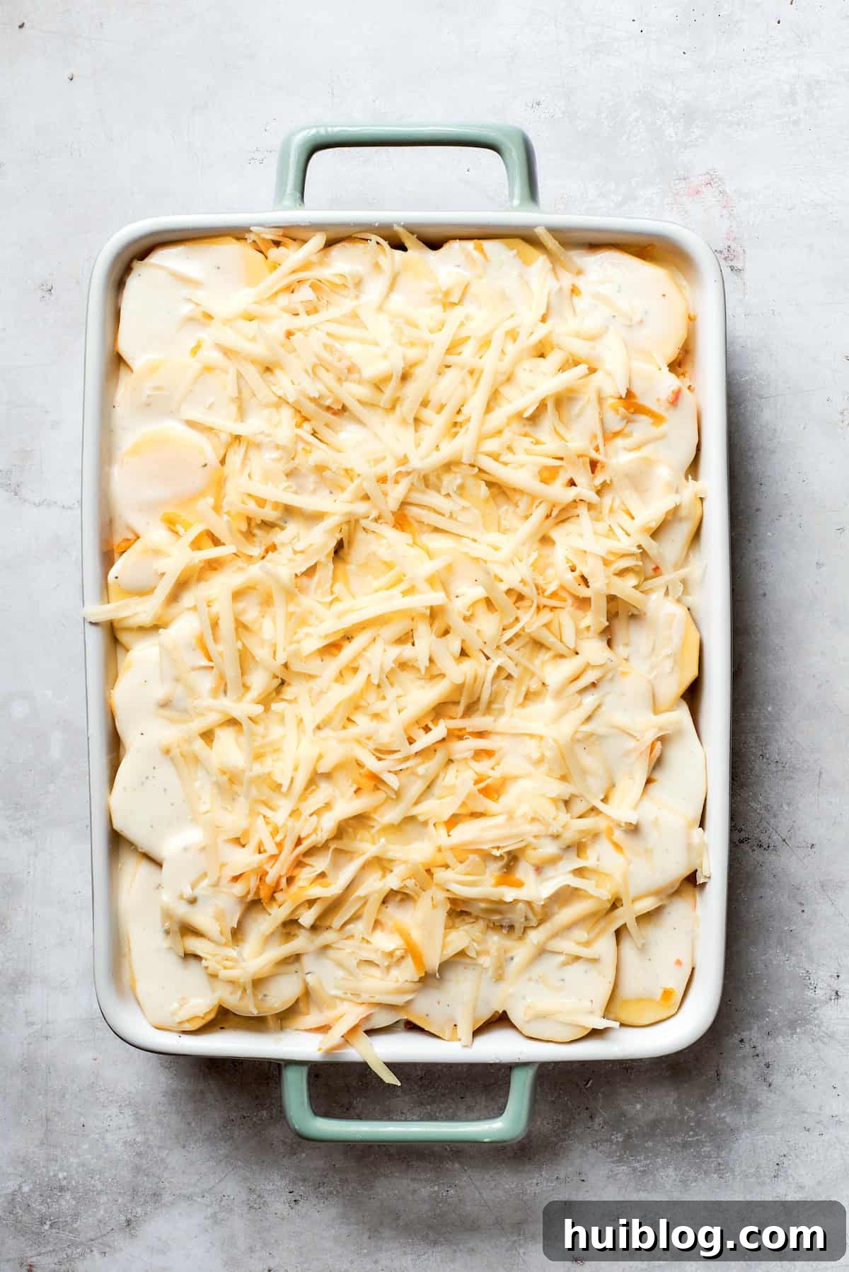 Hearty Ground Beef and Potato Bake 10 The final layer of shredded cheese is generously added to the top of the casserole, ready for baking.