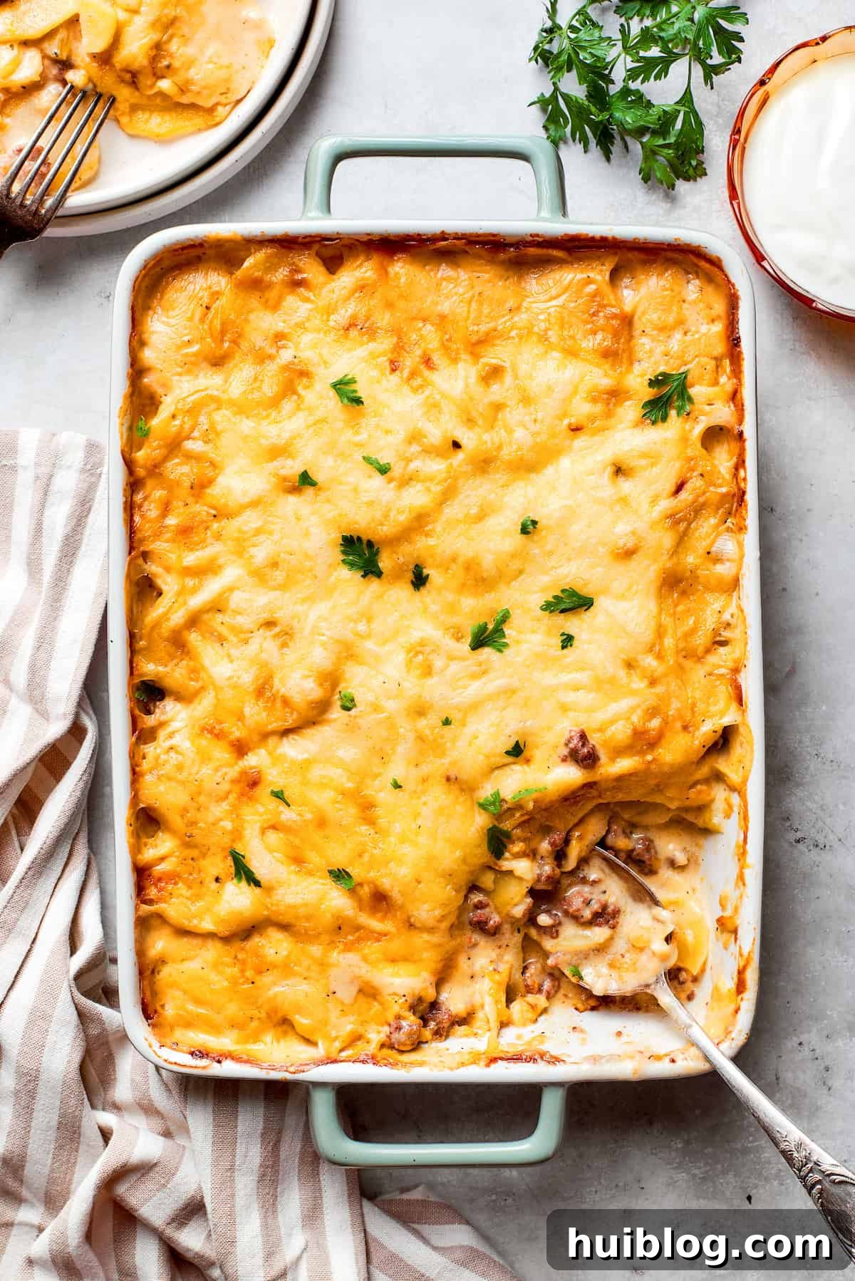 A large pan of hamburger potato casserole, perfectly baked with a golden brown, bubbly cheese topping.