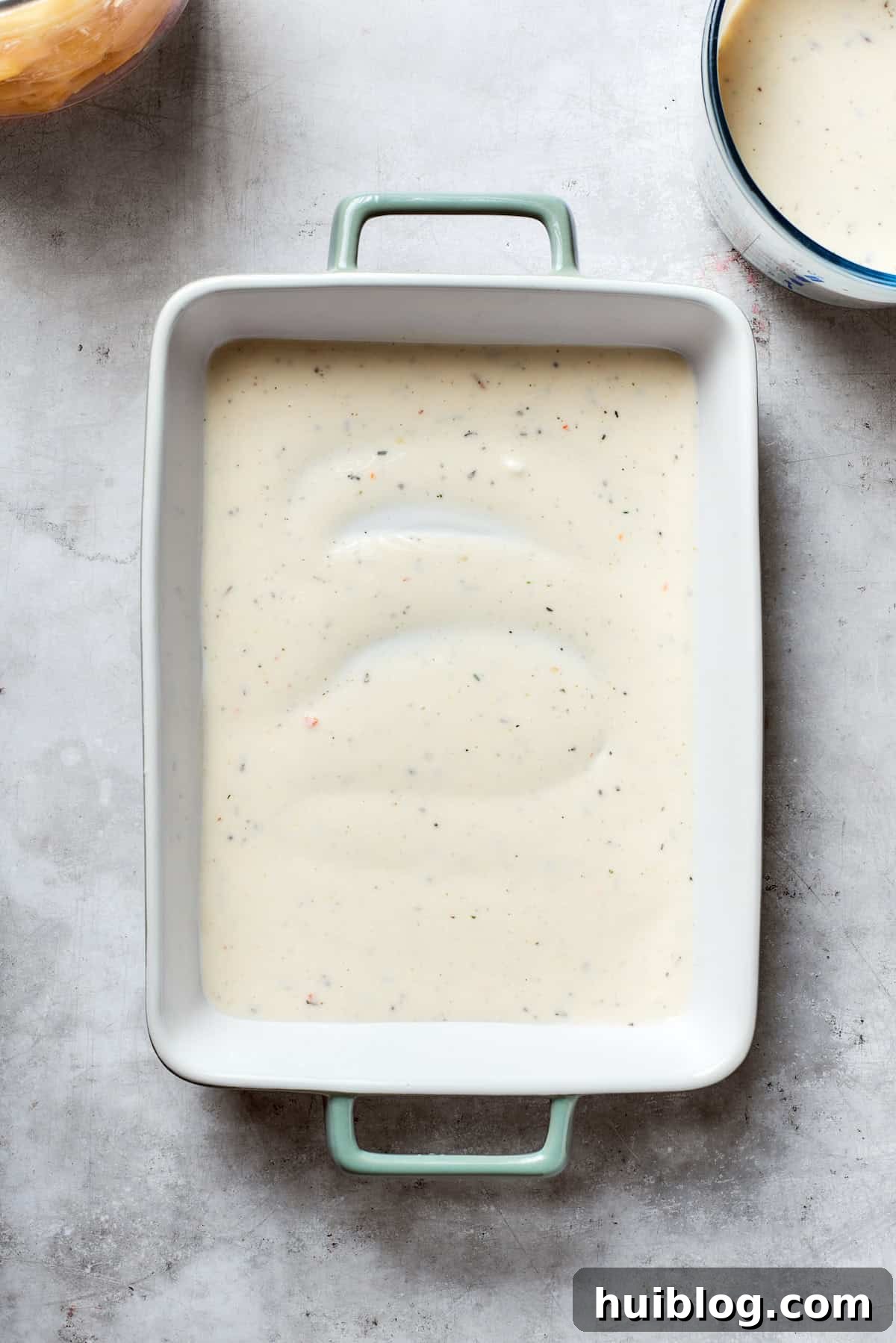 A thin layer of mushroom soup mixture is spread on the bottom of the baking dish.