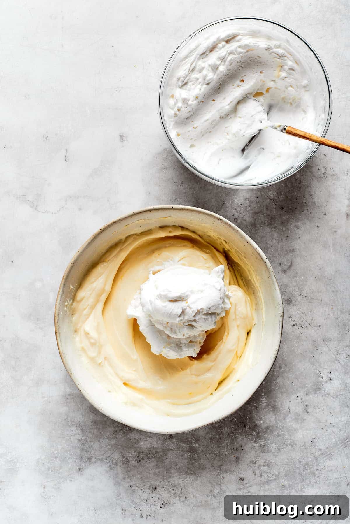 Lightly whipped heavy cream being gently folded into the mascarpone mixture to create a fluffy texture.