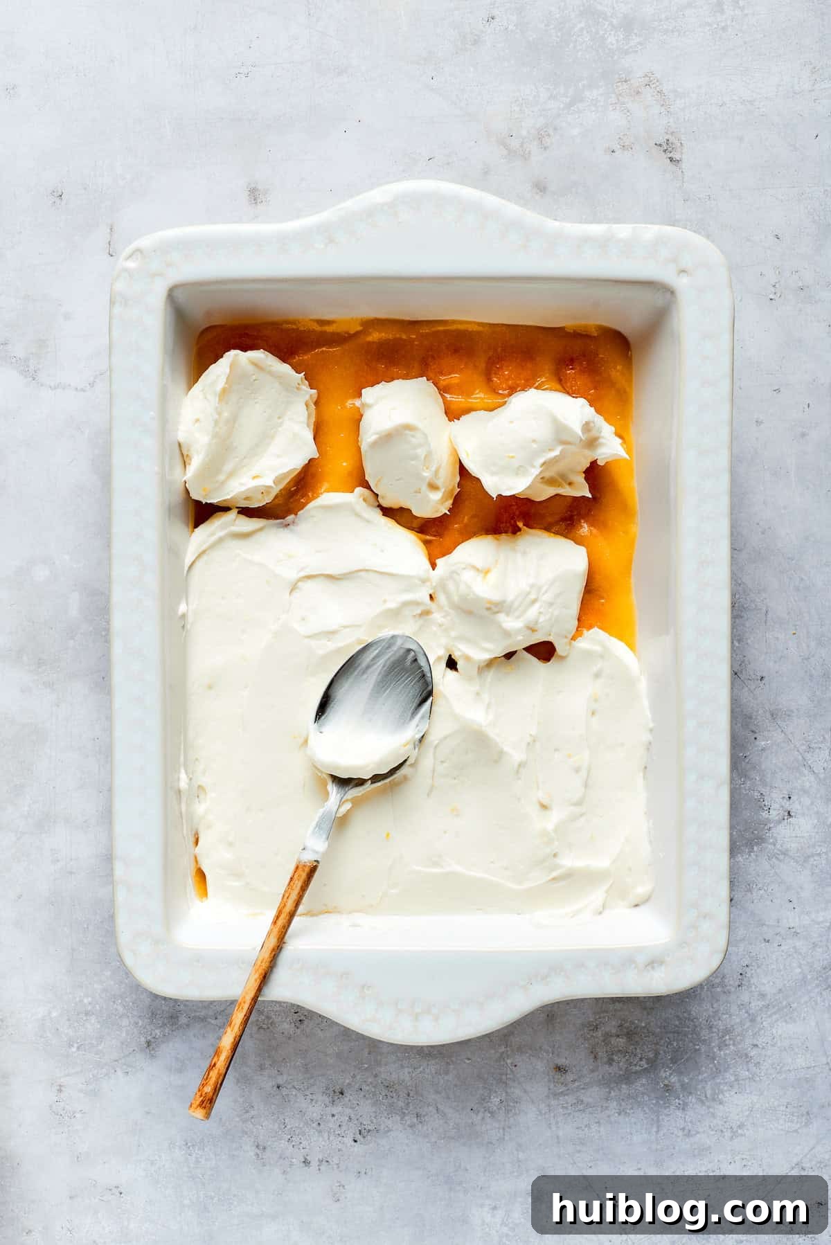 A generous, smooth layer of creamy mascarpone filling is spread over the lemon curd and ladyfingers.