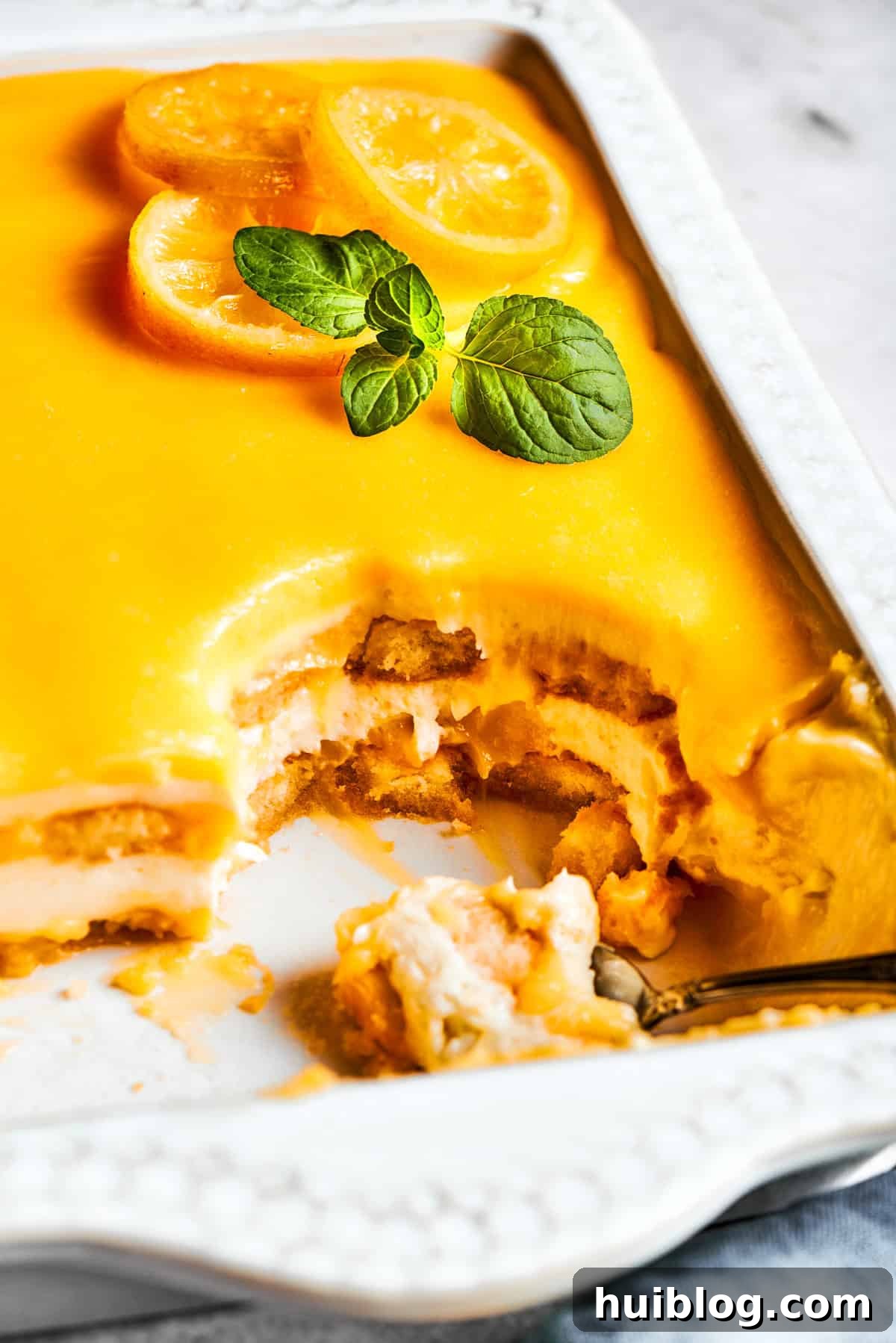 Half of a pan of lemon tiramisu, with several squares already cut and removed, showing the distinct layers.