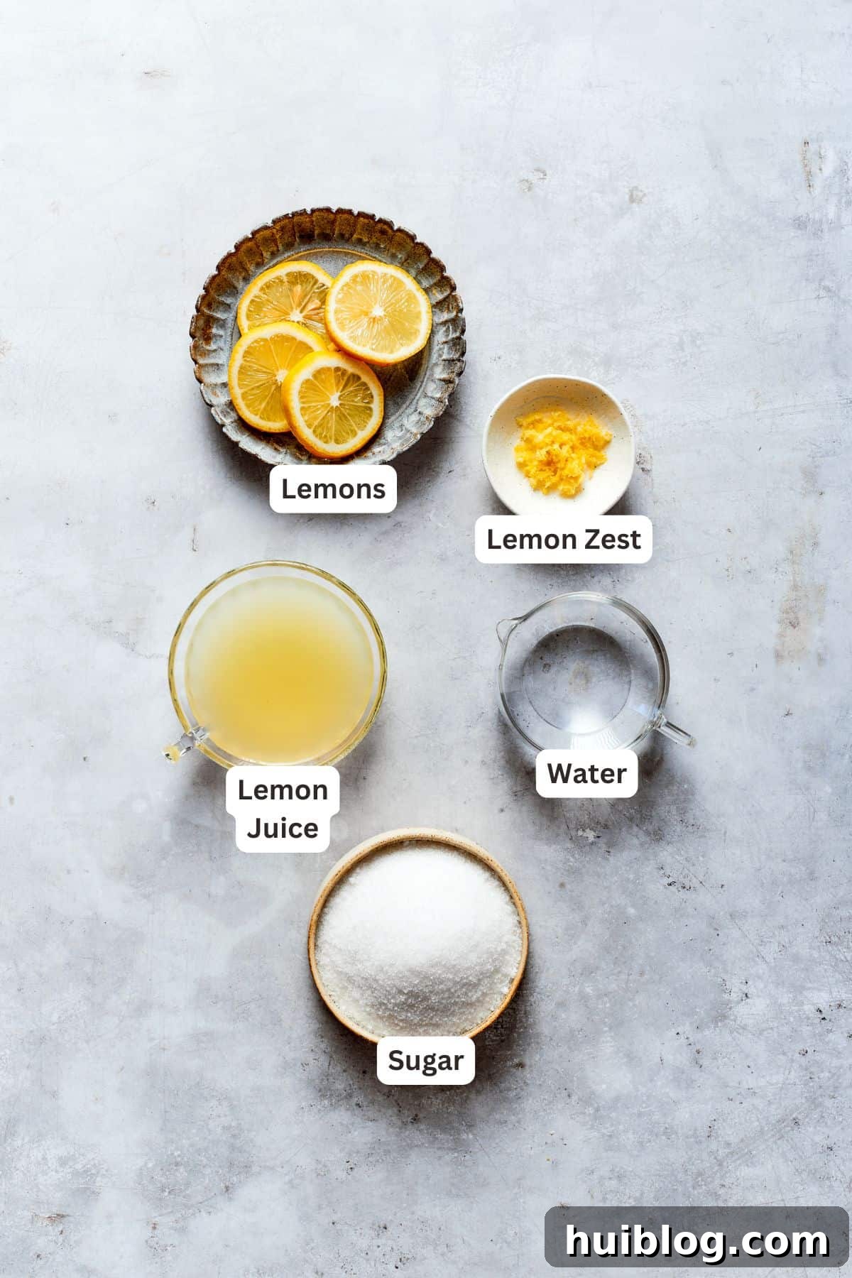 Ingredients for homemade lemon syrup including fresh lemons, granulated sugar, and water.