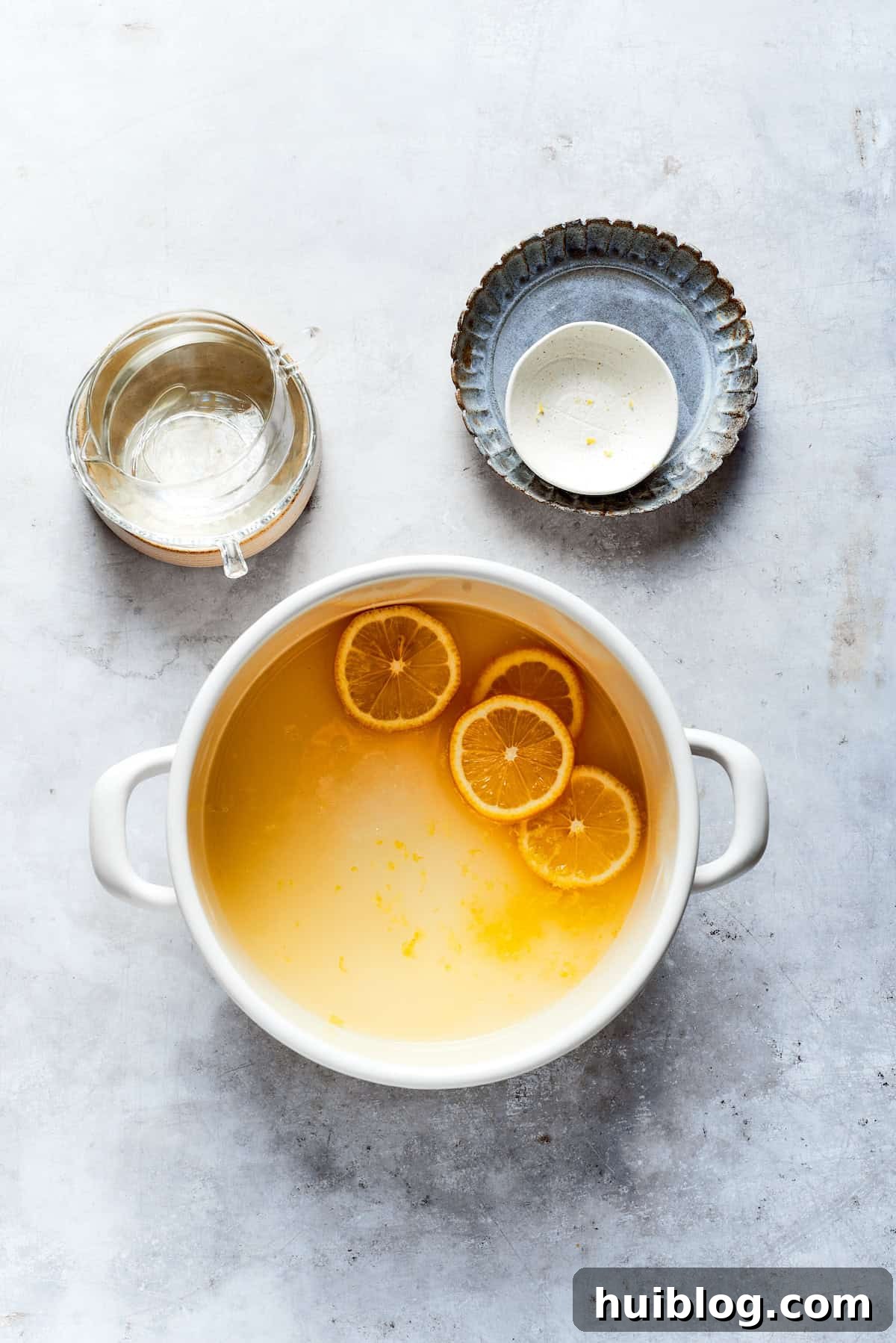Lemon juice, water, sugar, and lemon zest are simmering in a pot to create the lemon syrup.