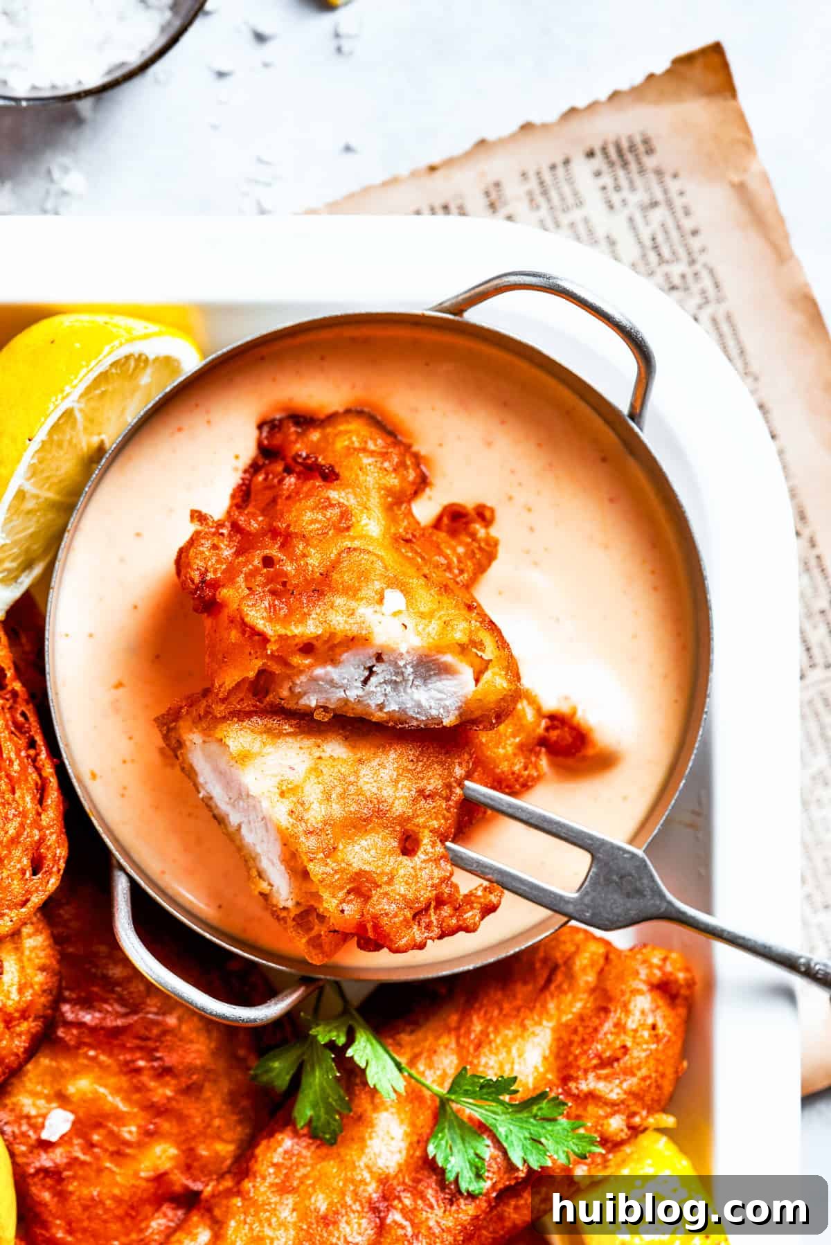 Light and crispy on the outside with a fork-tender inside, Beer Battered Chicken is an instant classic and so easy to make! A platter of beer, battered chicken, and a bowl of sauce.
