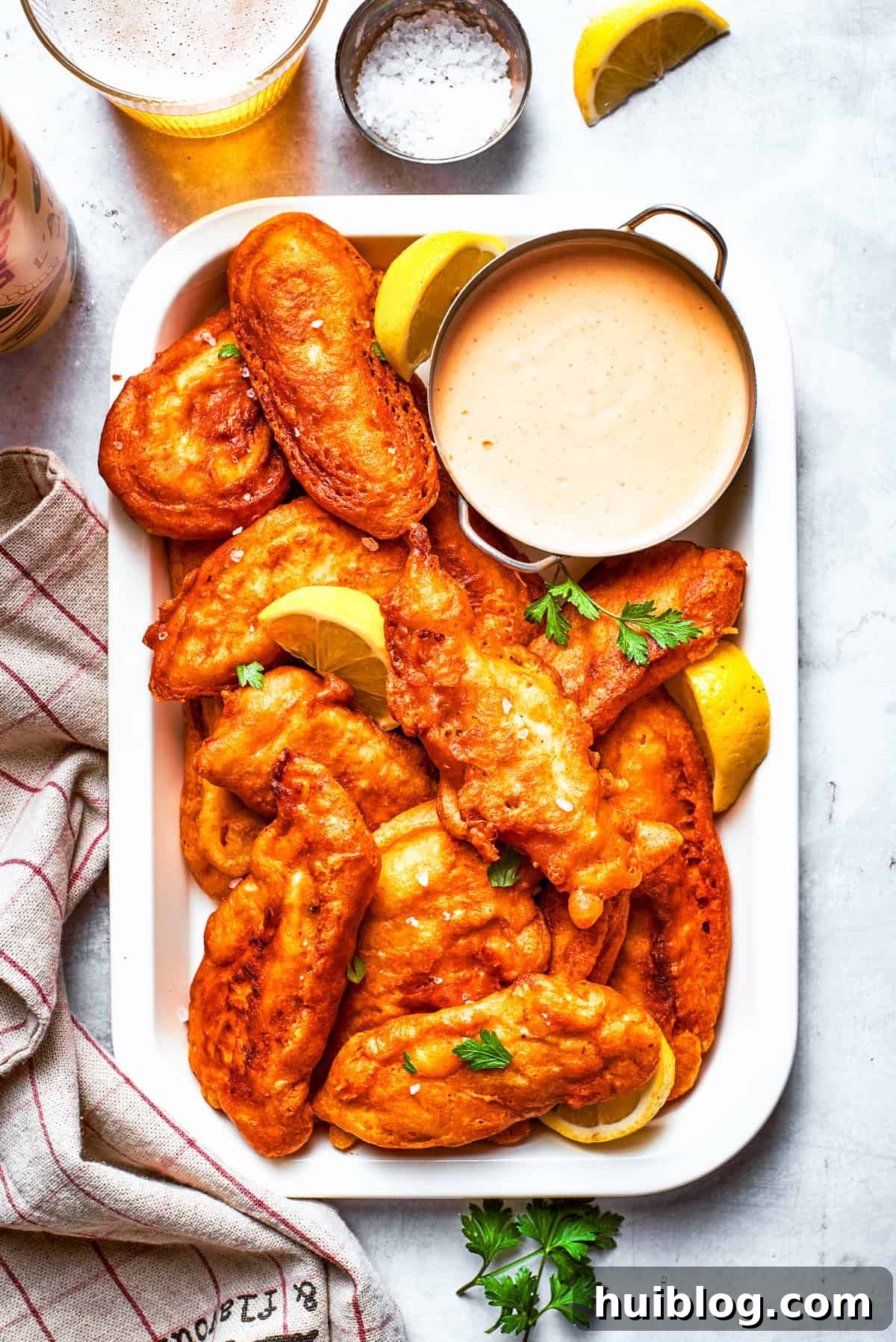 Light and crispy on the outside with a fork-tender inside, Beer Battered Chicken is an instant classic and so easy to make! Pieces of beer battered chicken arranged on a rectangular serving plate with a bowl of dipping sauce.