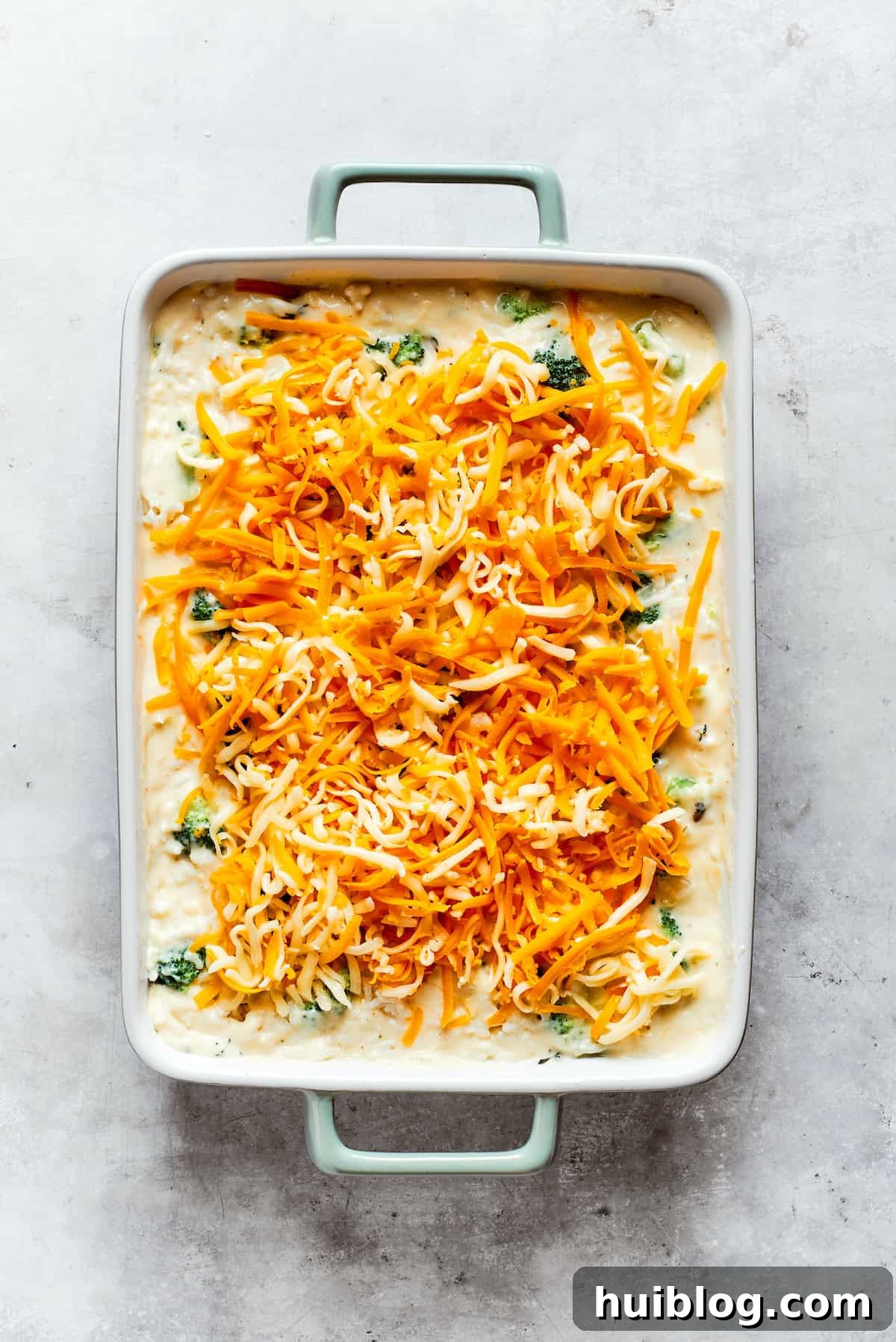 From-scratch Broccoli & Rice Casserole folds tender broccoli and fluffy white rice into a gorgeously creamy three-cheese sauce. Shredded cheddar cheese is generously sprinkled over the top of the assembled broccoli and rice casserole, ready for baking to a golden, bubbly finish.