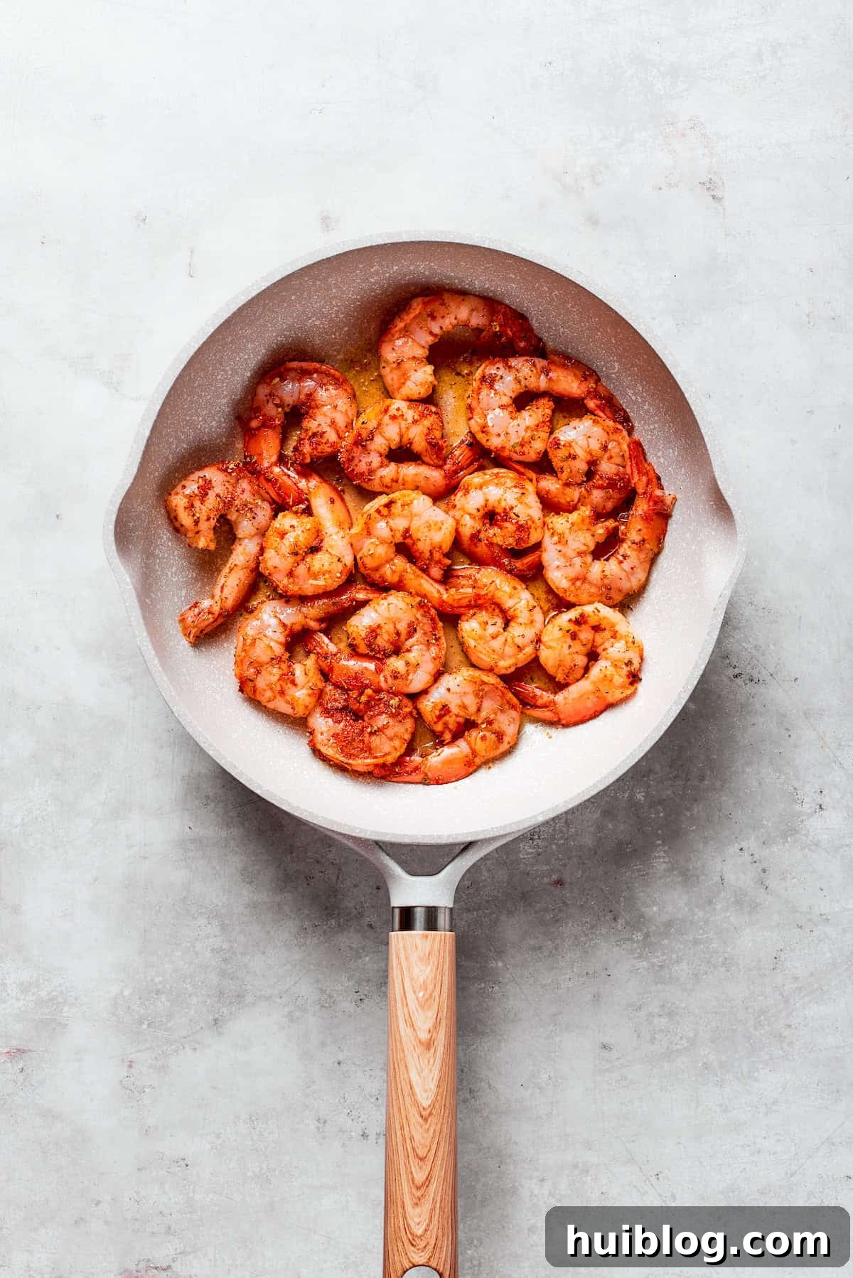 Seasoned shrimp cooks in a skillet.