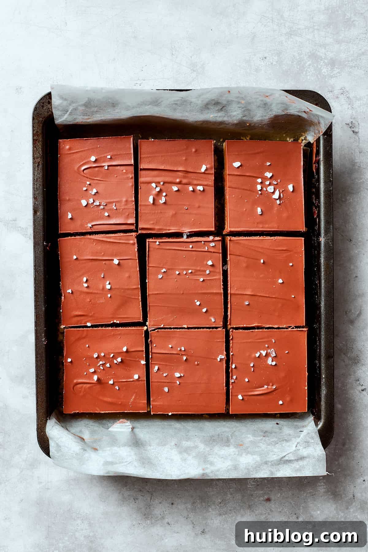 A final layer of chocolate ganache, sprinkled with flaky sea salt, covers the caramel in a pan of millionaire bars.