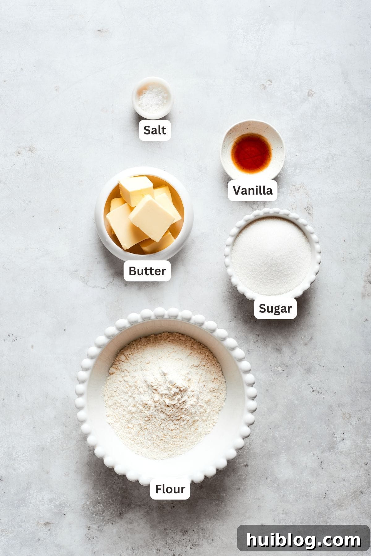Labeled ingredients for the shortbread crust, including butter, sugar, vanilla, salt, and flour, neatly arranged on a kitchen surface.