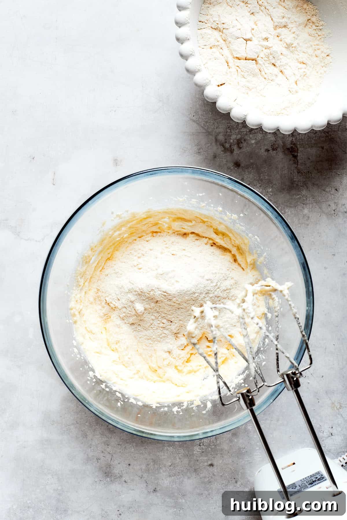 Sugar is being mixed into softened butter in a mixing bowl, an initial step for the shortbread crust.