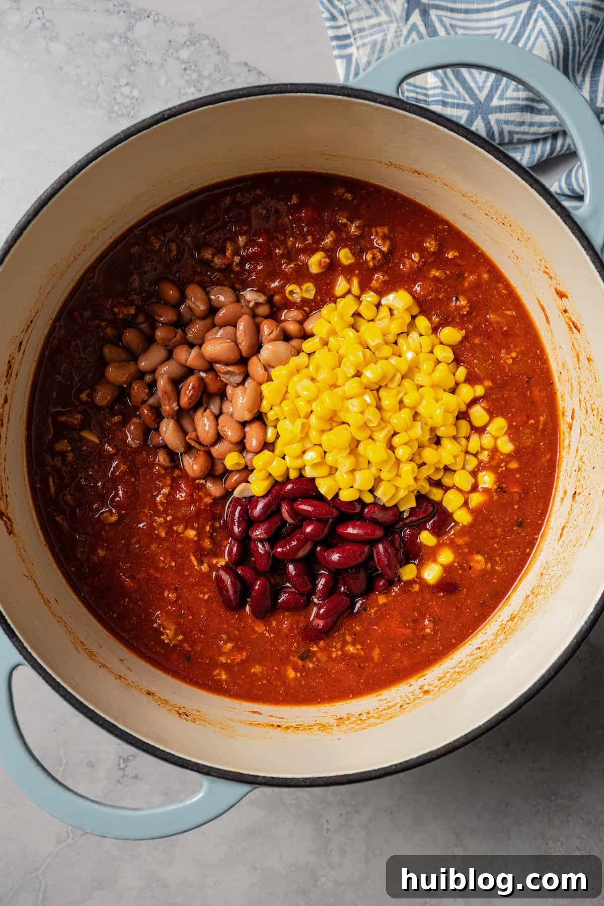 Canned corn and beans added to a pot with turkey chili.