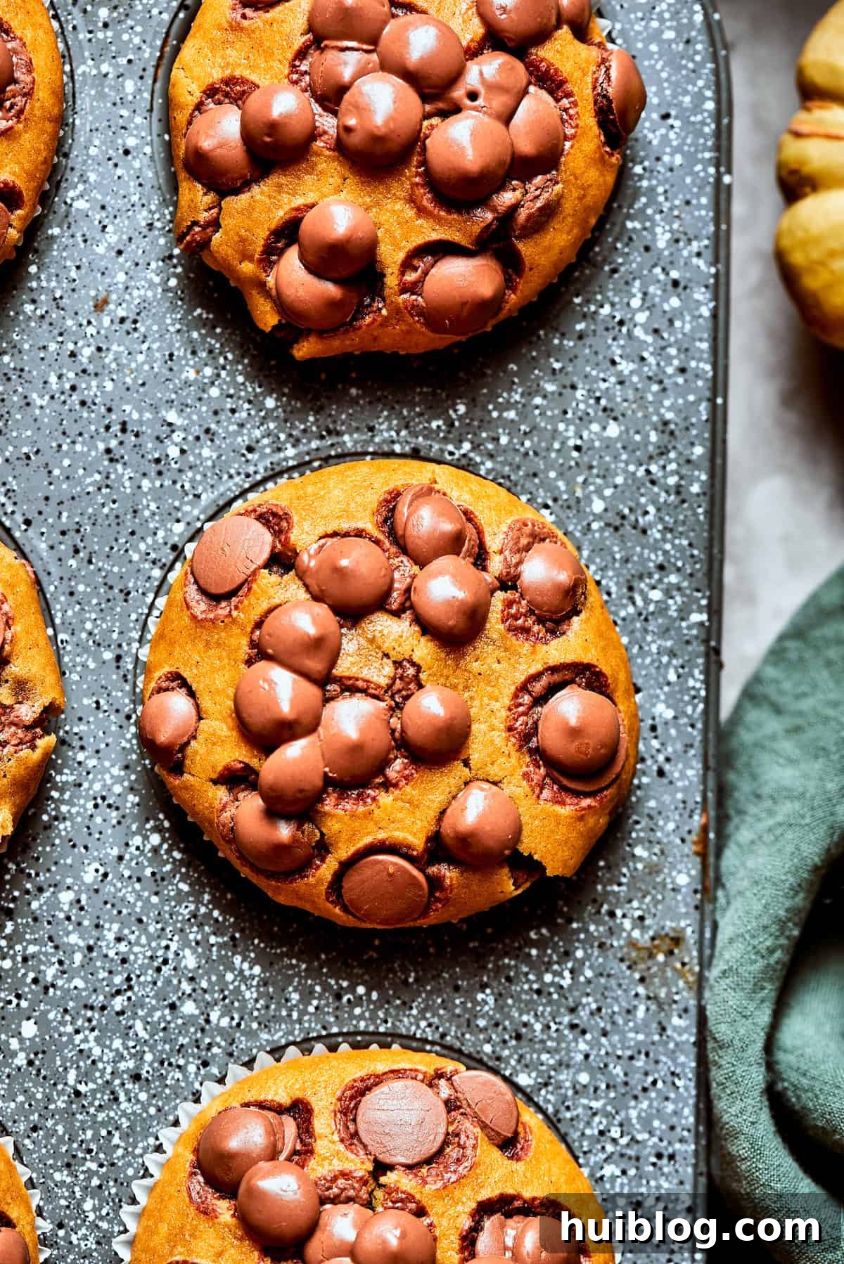 Three pumpkin chocolate chip muffins in a muffin tin.