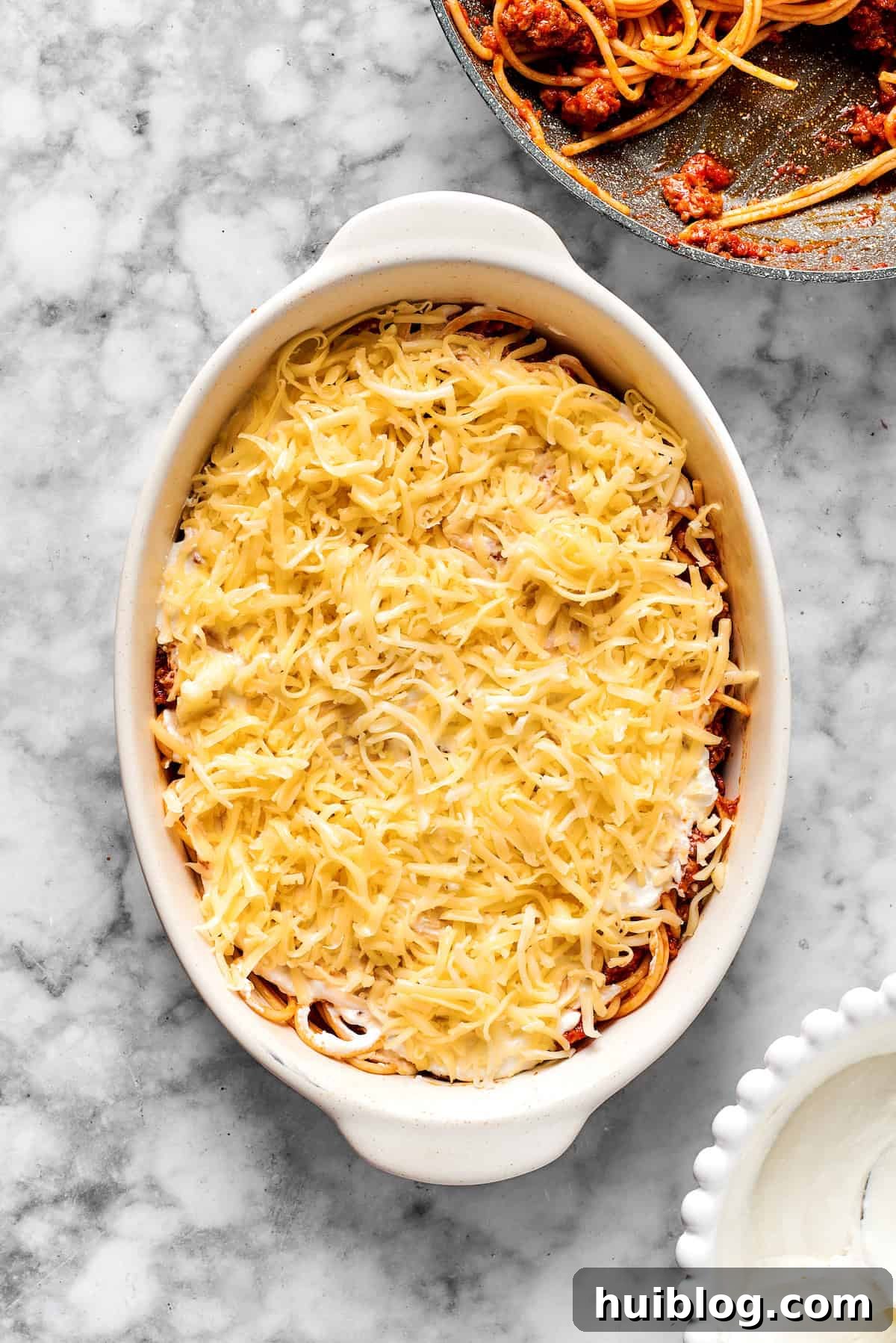 Adding a layer of shredded cheese on top of spaghetti in a 9x13 dish before baking.