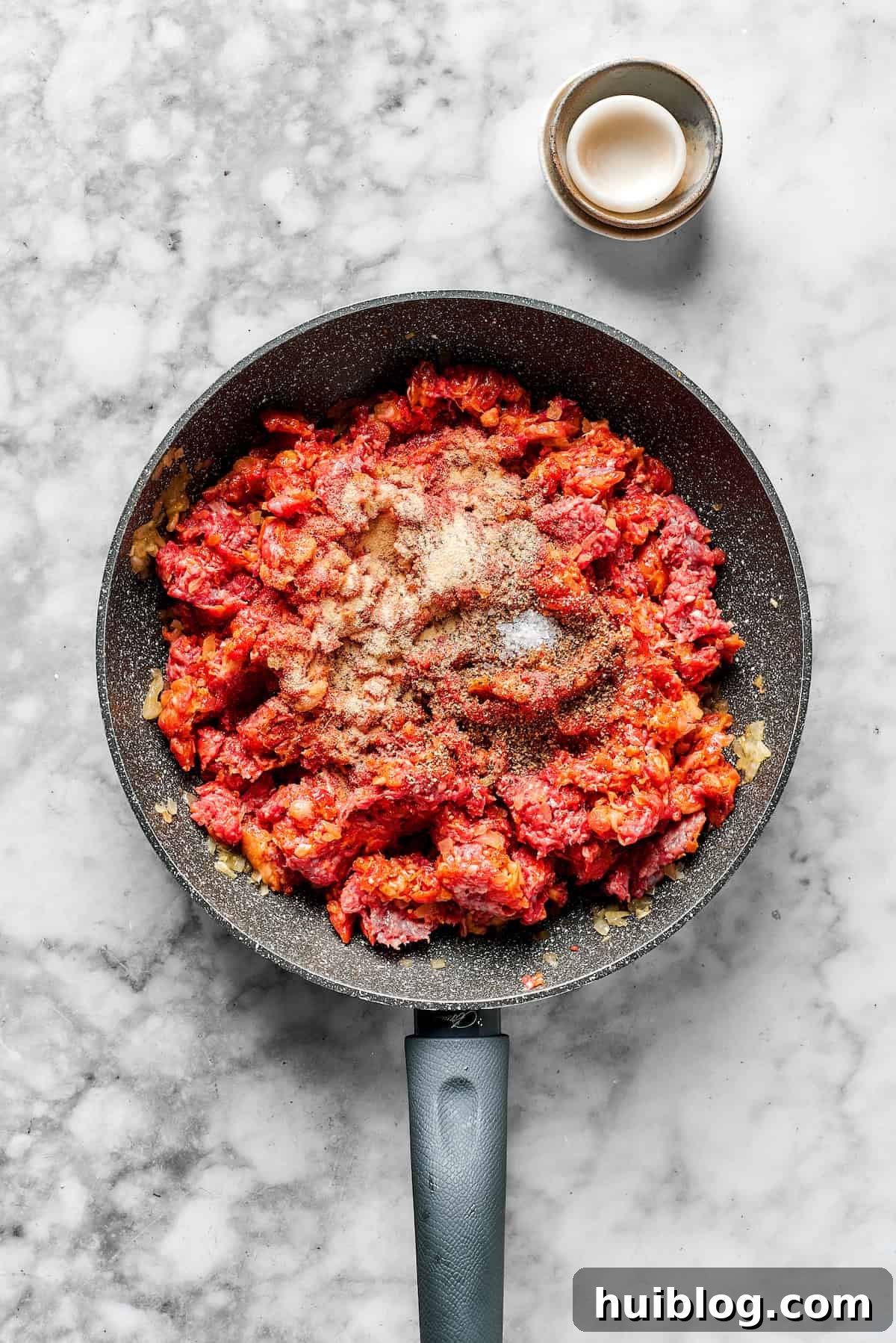 Breaking up the meat and adding spices to the skillet.