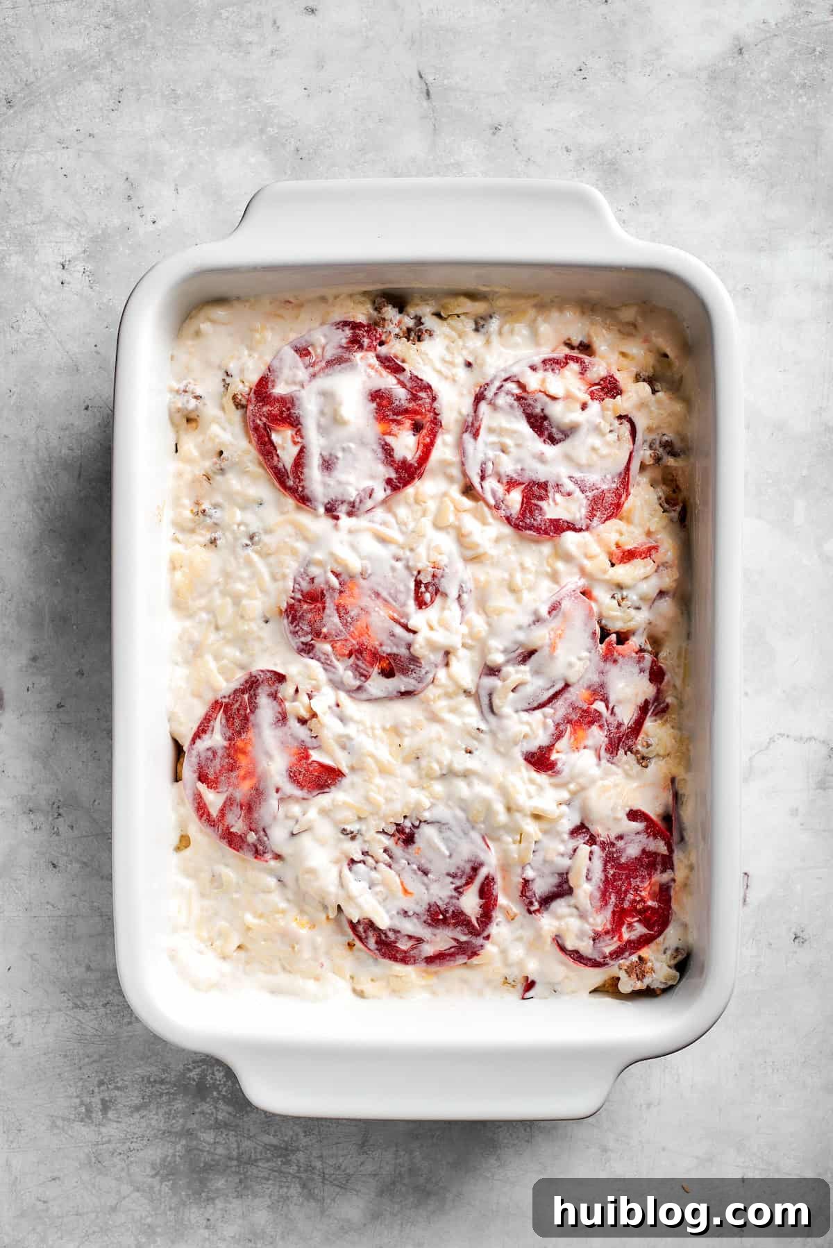 Spreading the sour cream and mayonnaise mixture over the tomato layer.