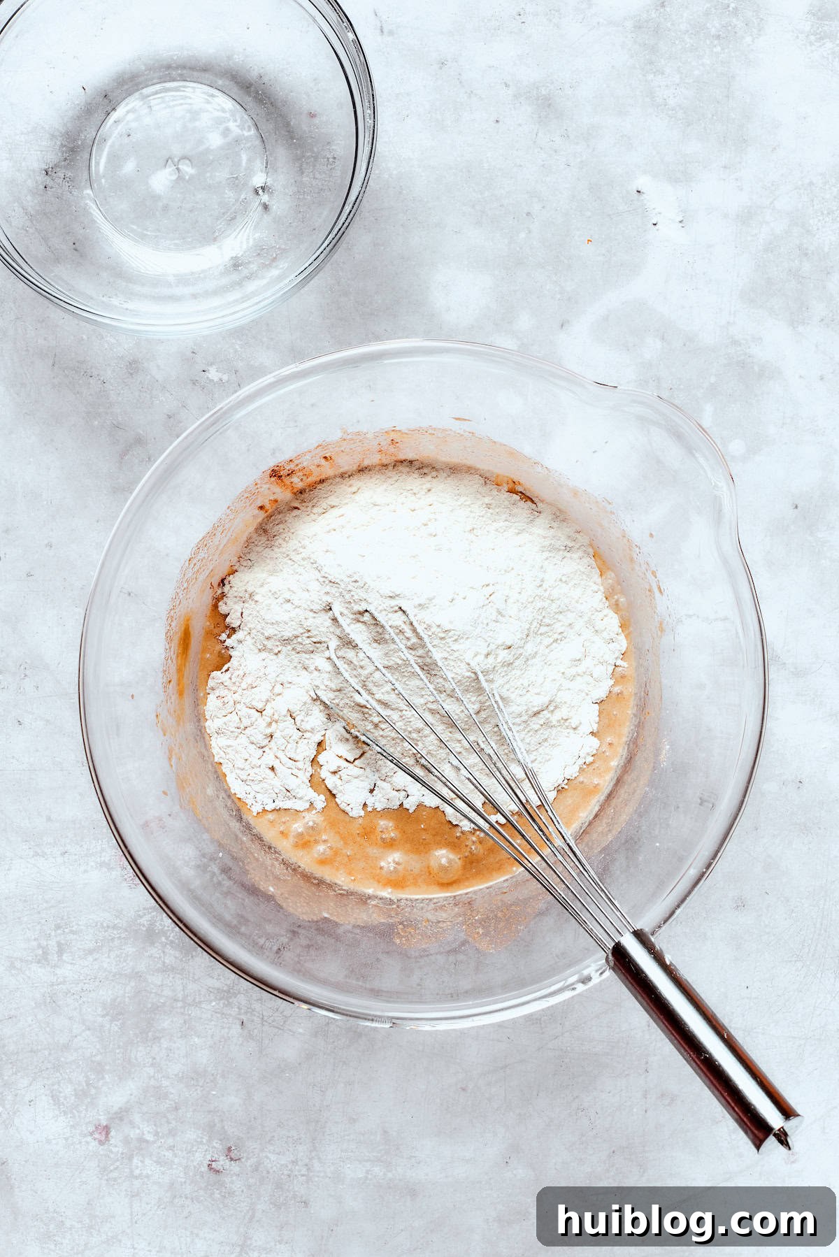 Dry ingredients are gradually folded into the wet donut batter, ensuring not to overmix.