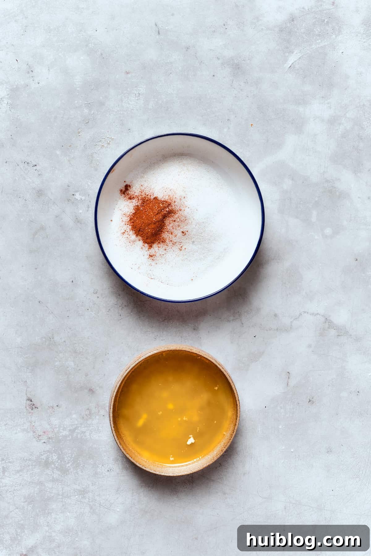 Two bowls are shown: one with melted butter, and the other with a mixture of granulated sugar and cinnamon for the topping.