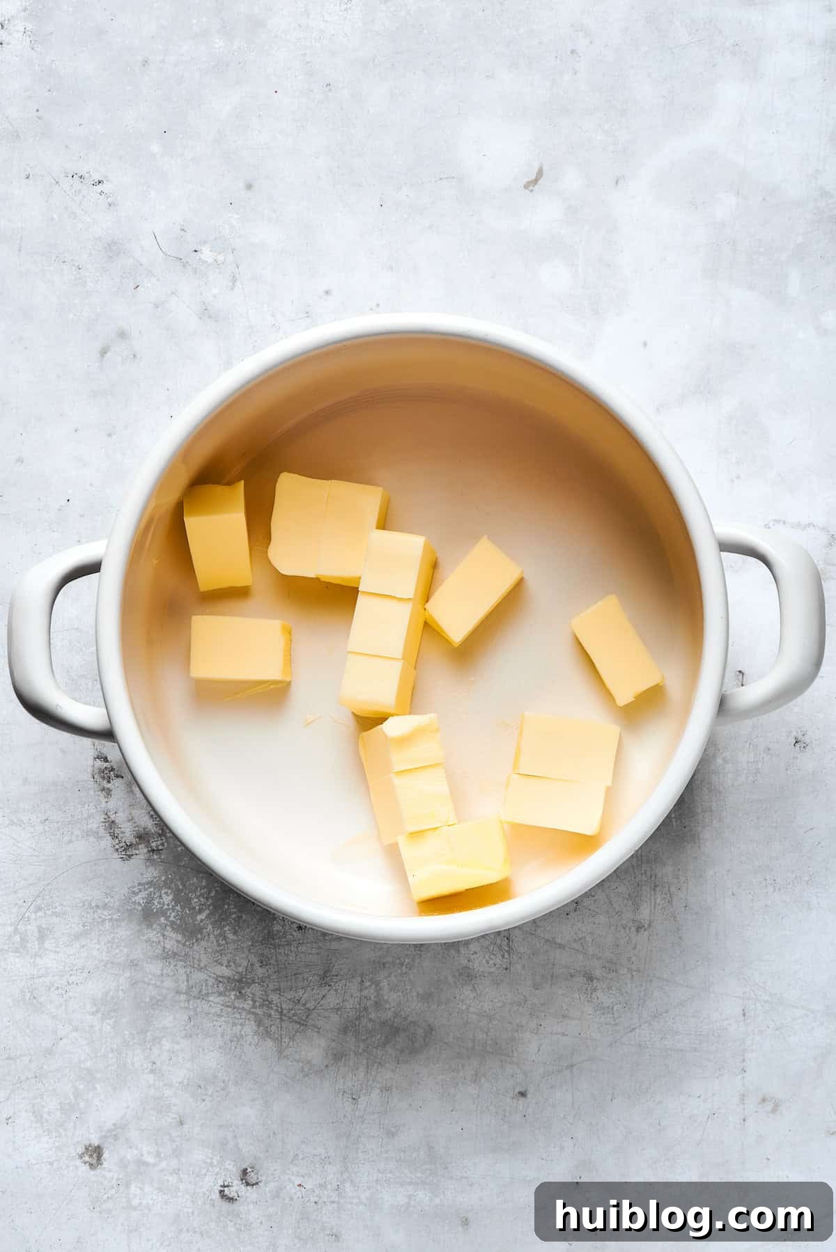 Pieces of unsalted butter melting gently in a saucepan over medium heat, beginning the process of browning.