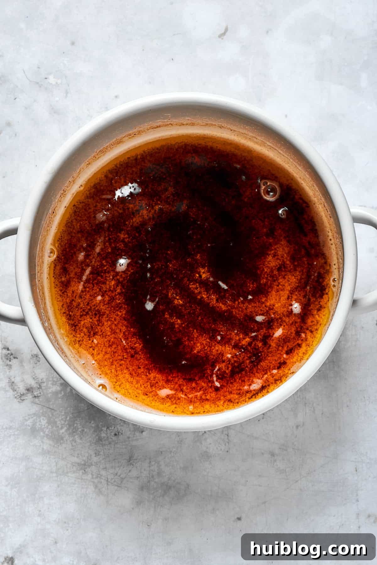 A pot of deeply browned butter with toasted milk solids visible at the bottom, indicating a rich, nutty flavor.