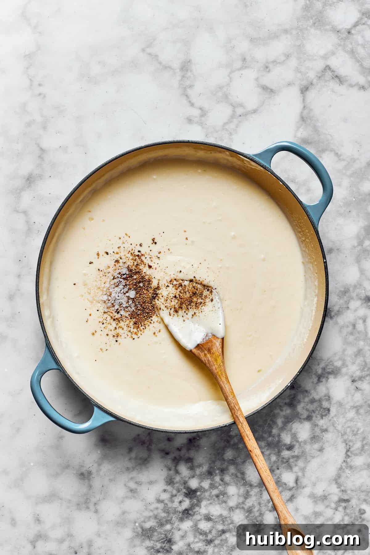 Season to taste. A creamy pasta sauce being seasoned with salt and black pepper from shakers, ensuring perfect taste balance.