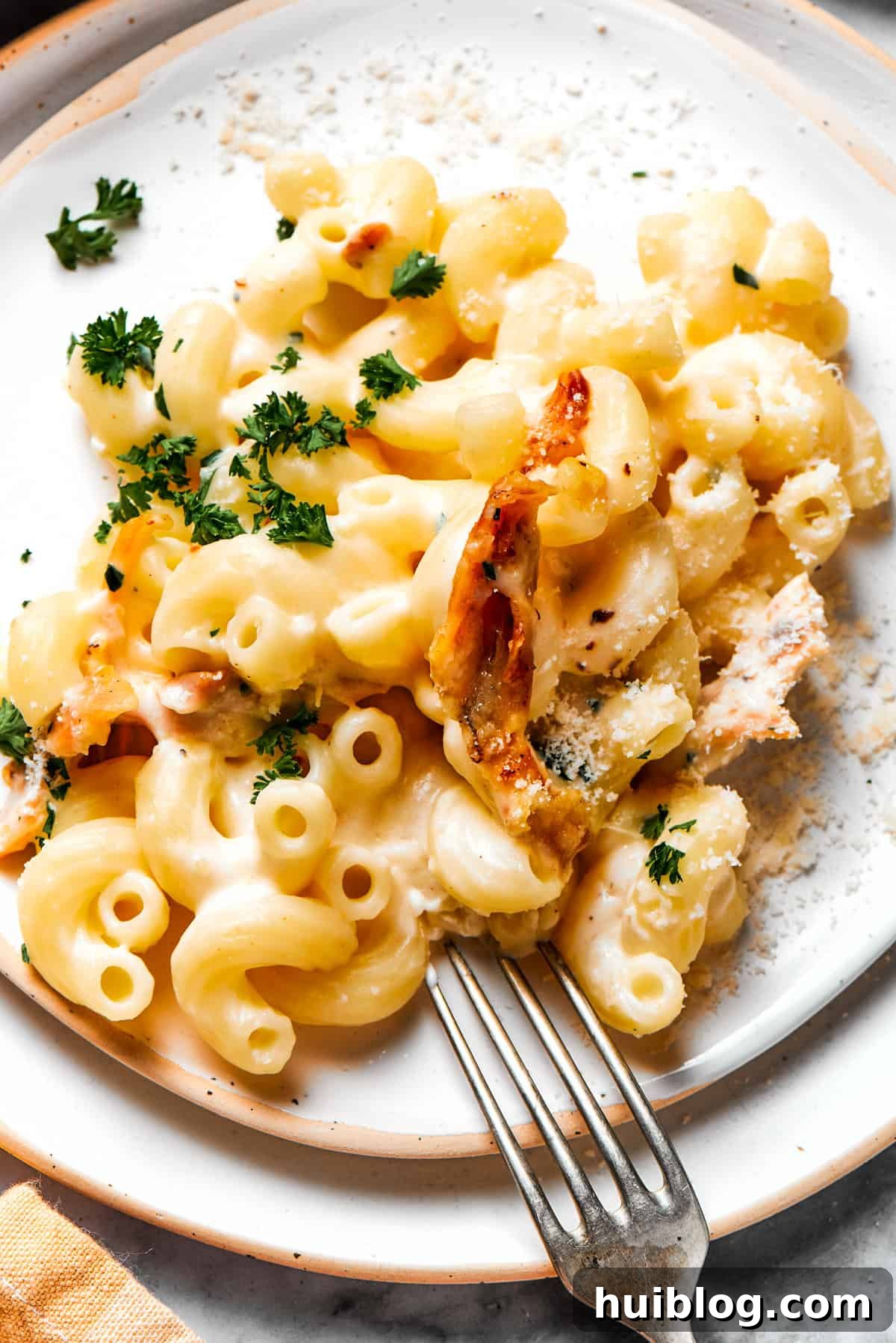 Garlic parmesan chicken pasta served on a dinner plate. A generous serving of creamy garlic parmesan chicken pasta, garnished with fresh parsley, on a white dinner plate, ready to be enjoyed.