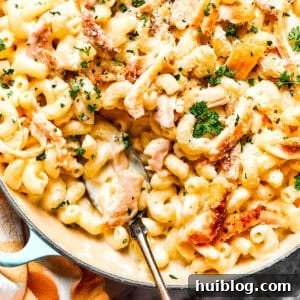 Creamy Garlic Parmesan Chicken Pasta 2 Close-up image of parmesan chicken pasta in a skillet, with a serving spoon resting inside the skillet.