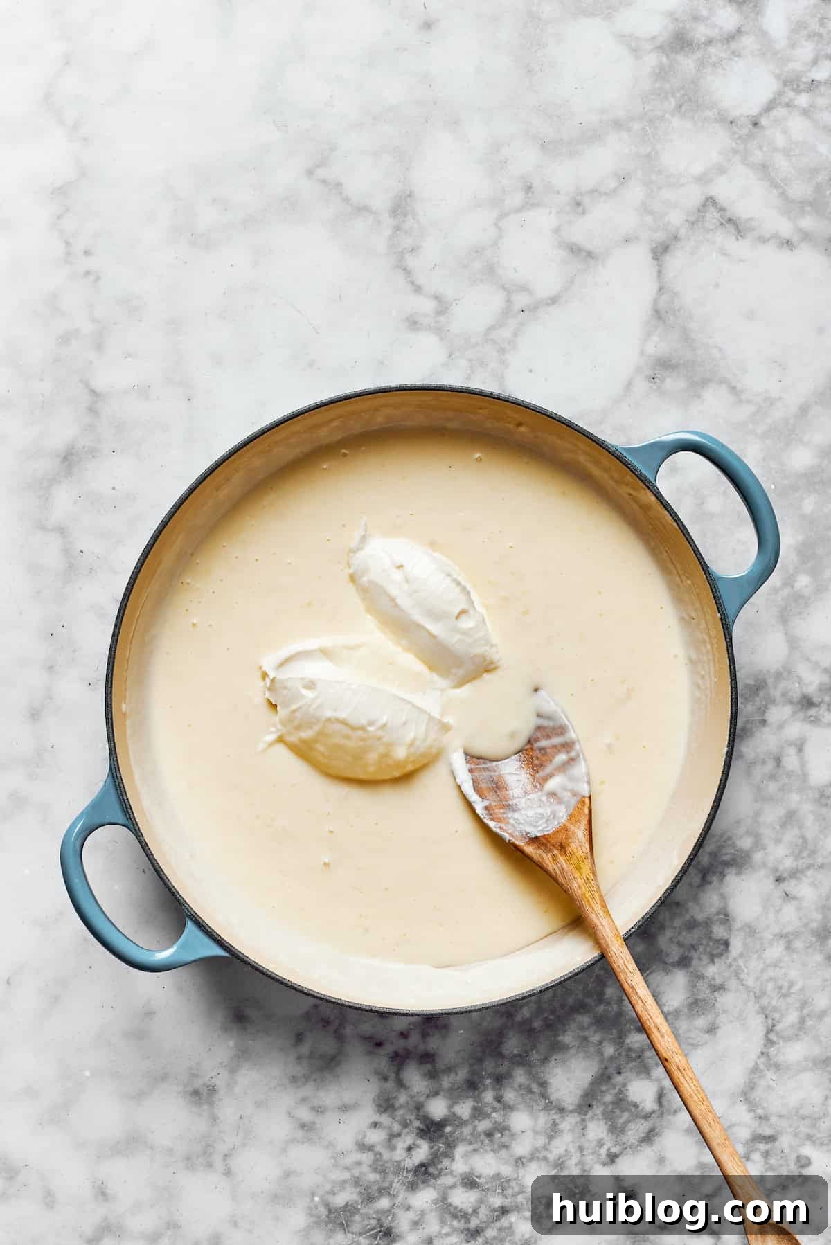Add parmesan & cream cheese. Cubed cream cheese being added to a rich, creamy sauce in a saucepan, preparing for the final cheesy infusion.