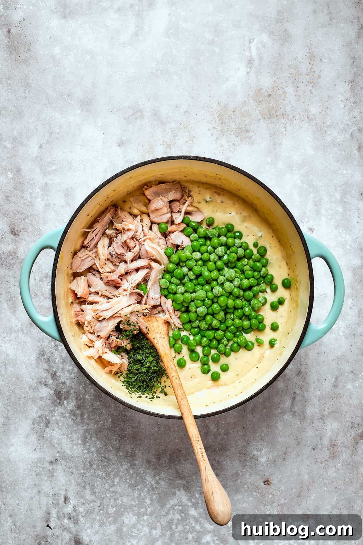 Hearty Chicken Pot Pie Casserole 8 Cooked shredded chicken and frozen peas being stirred into the pot pie filling.