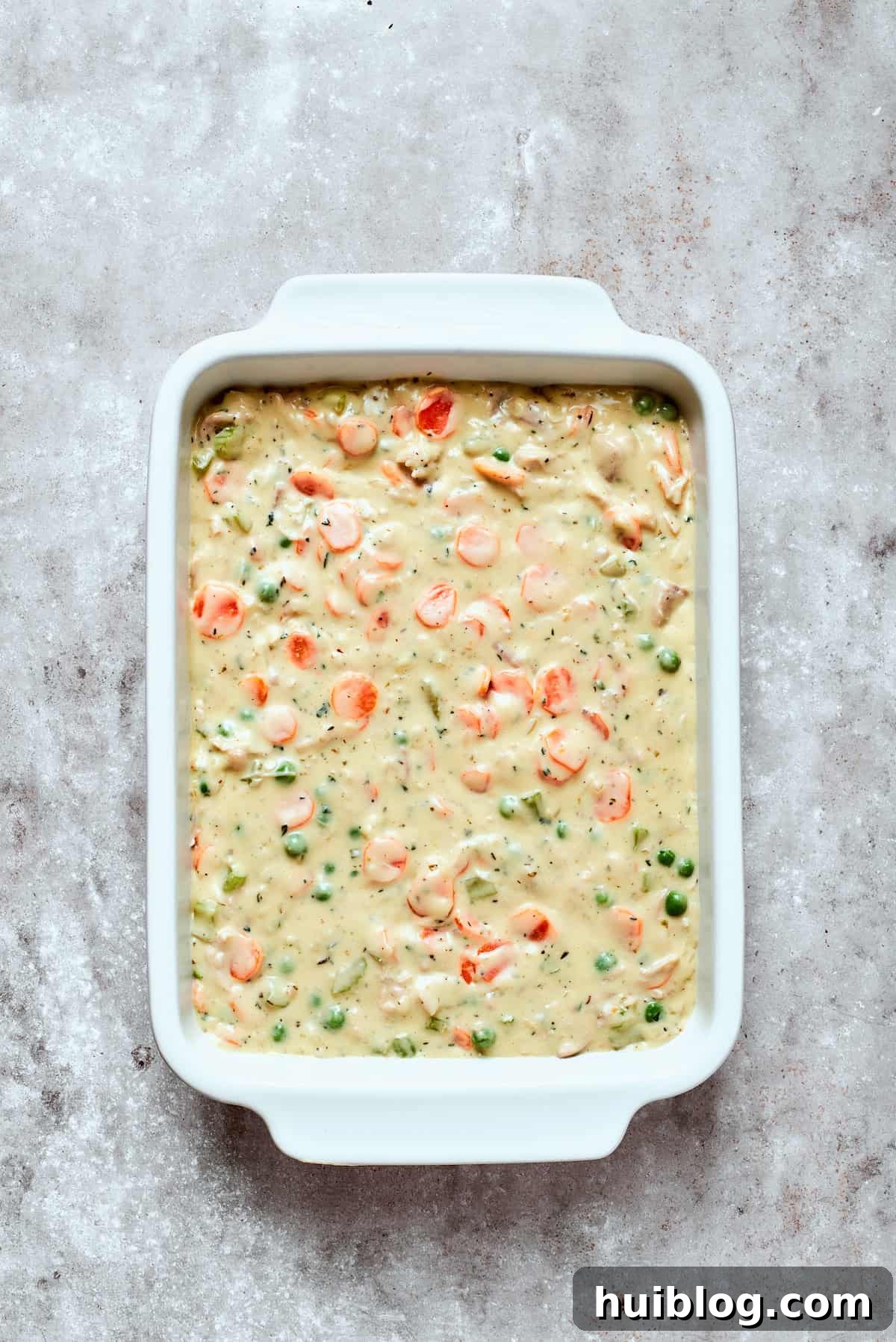 Hearty Chicken Pot Pie Casserole 9 The prepared chicken pot pie filling poured into a buttered baking dish, ready for biscuit topping.