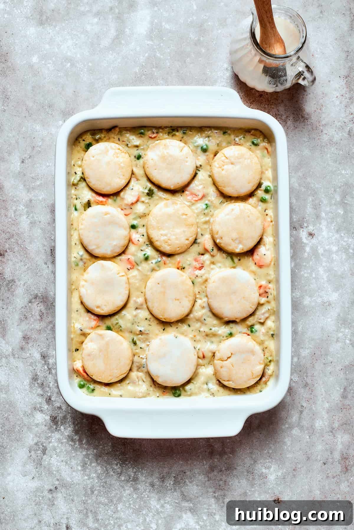 Hearty Chicken Pot Pie Casserole 13 Assembled chicken pot pie casserole with biscuits on top, ready for baking.