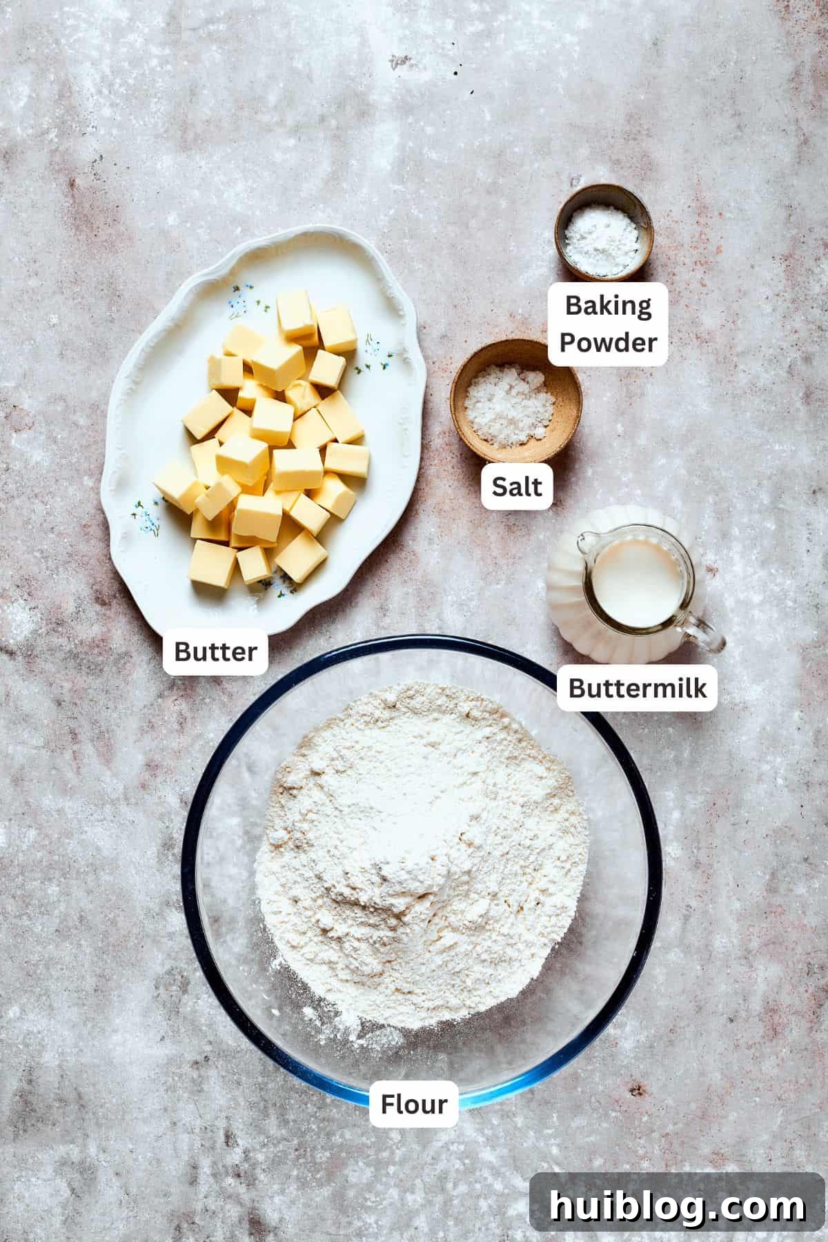 Buttermilk Biscuit Essentials Ingredients for making homemade buttermilk biscuits, including butter, flour, baking powder, salt, and a measuring cup of buttermilk.