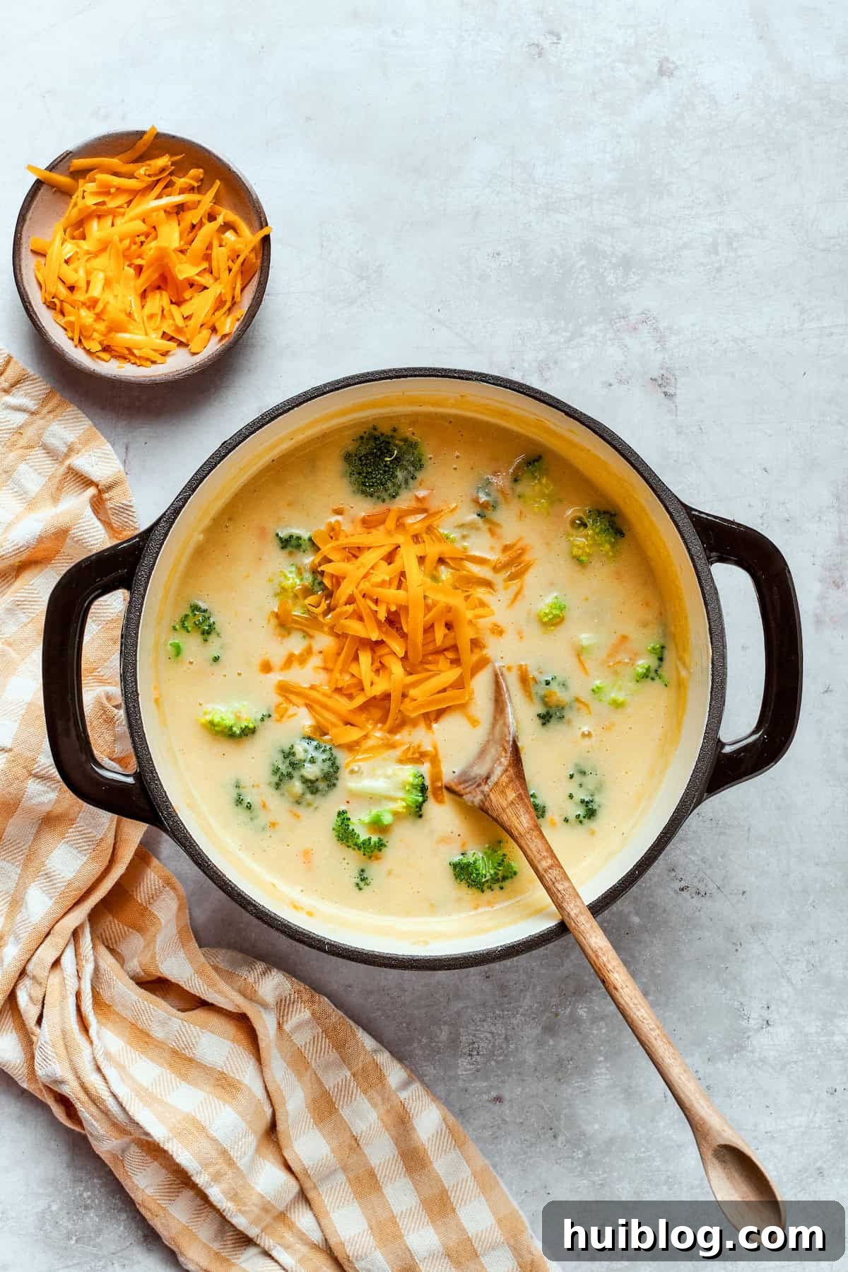 Adding a generous amount of shredded cheddar cheese to the hot soup, stirring until fully melted and creamy.