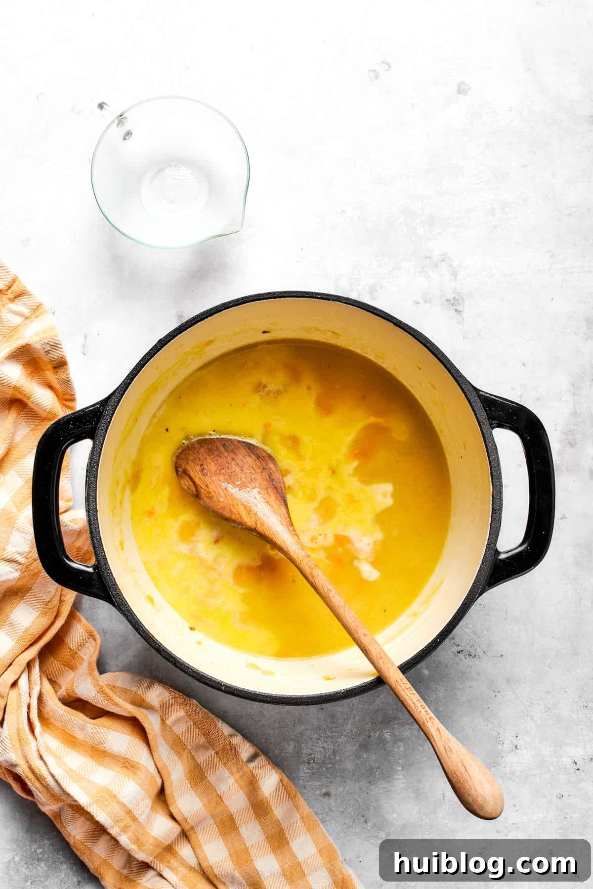 Adding milk to the simmering soup base, stirring to combine for a rich, creamy texture.