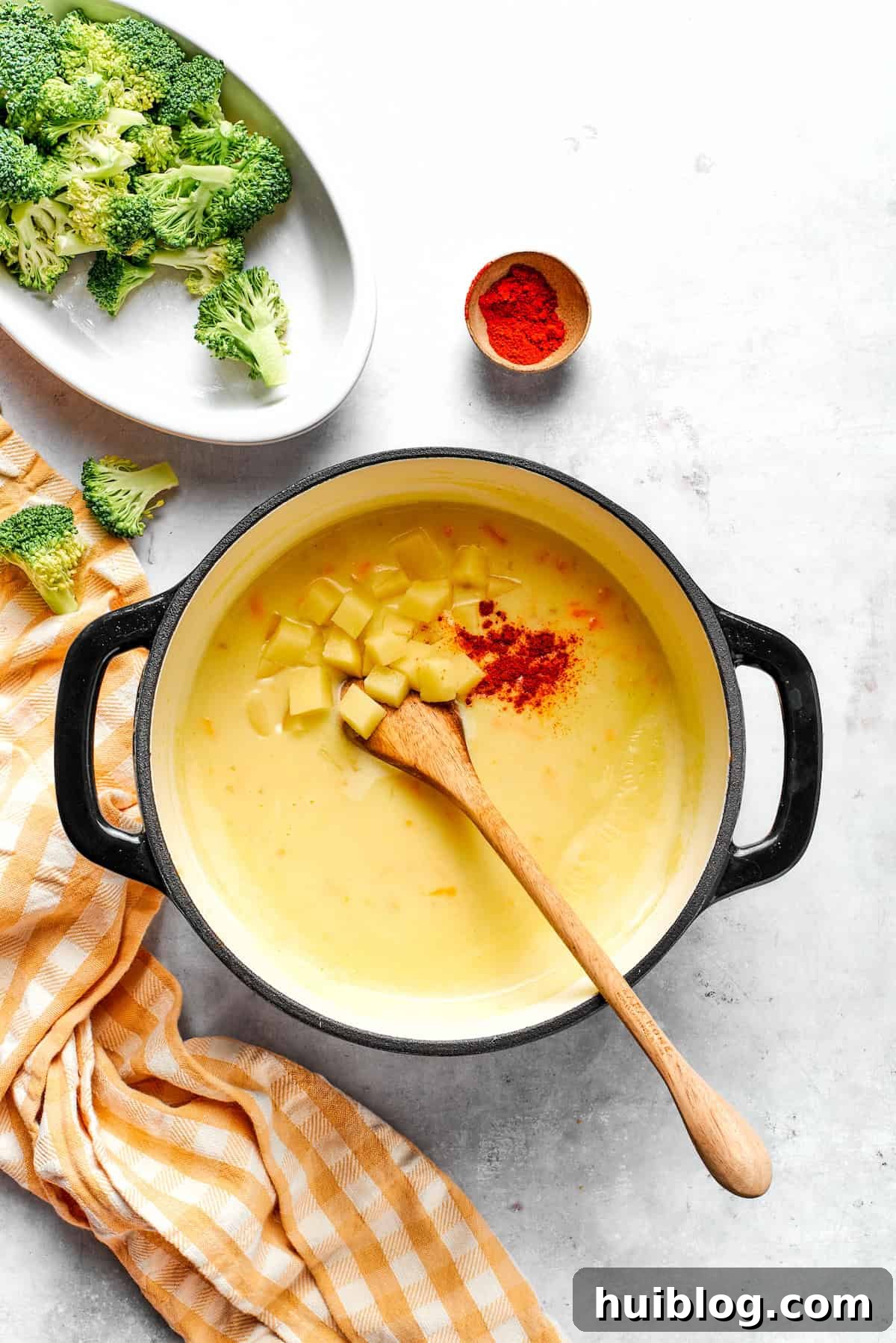Diced potatoes and smoked paprika being added to the simmering soup, enhancing flavor and heartiness.
